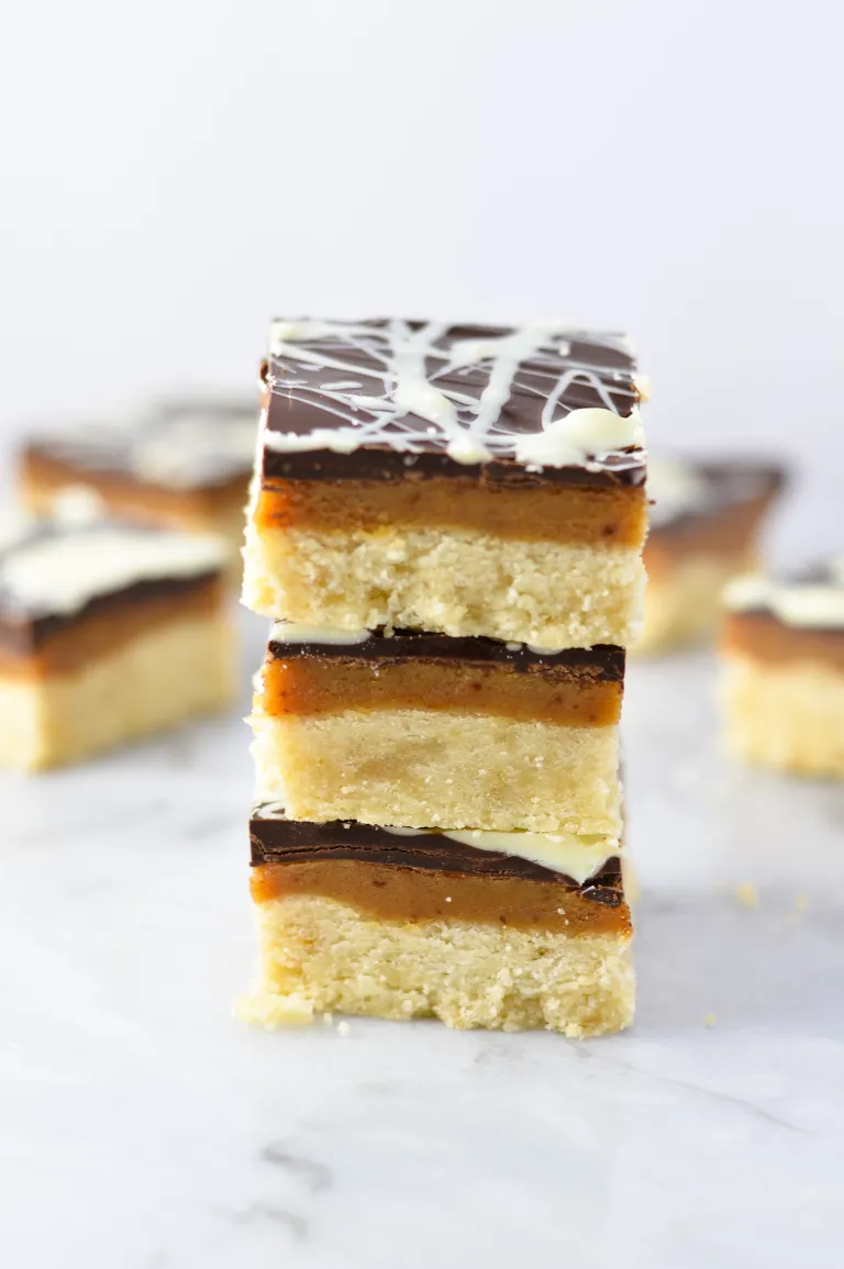 Stack of white chocolate swirl millionaire bars on a marble surface.