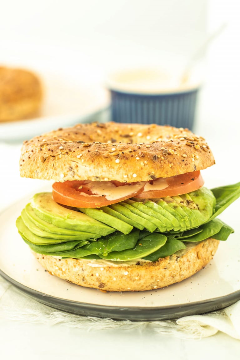 Avocado bagel sandwich on a plate.