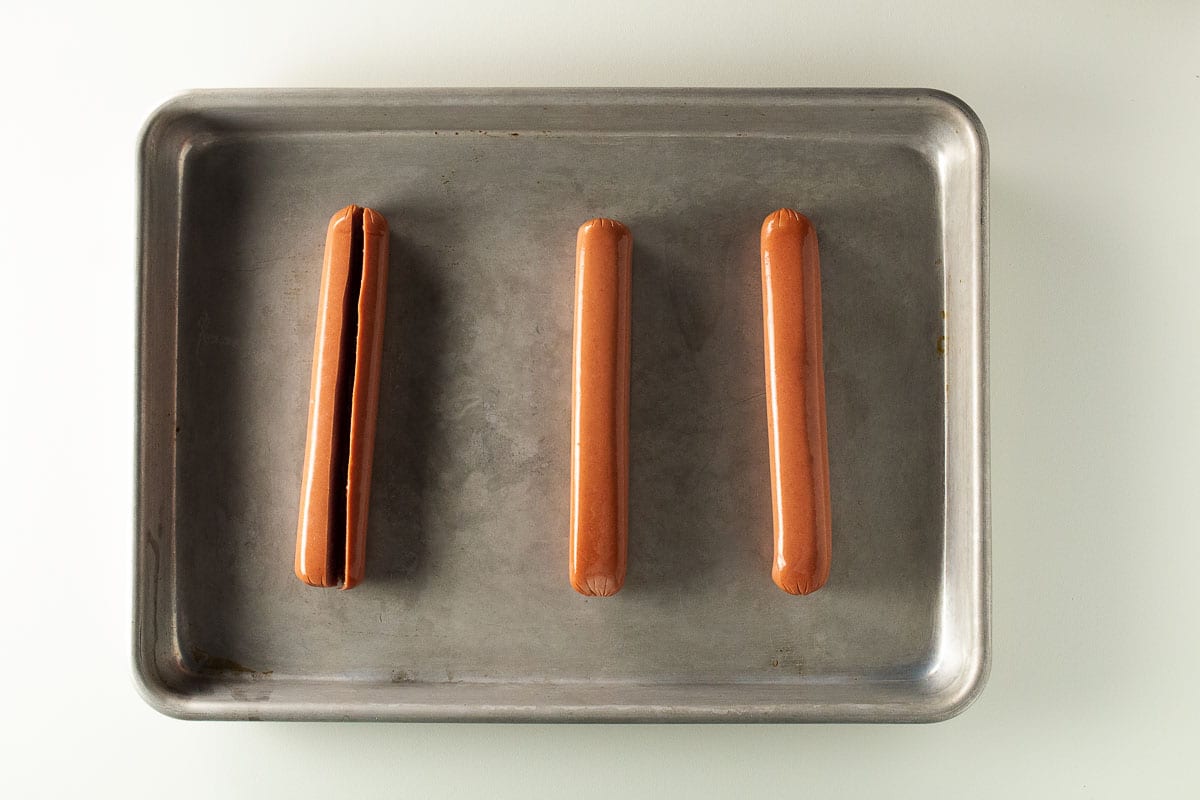 Split hot dogs on a baking pan.