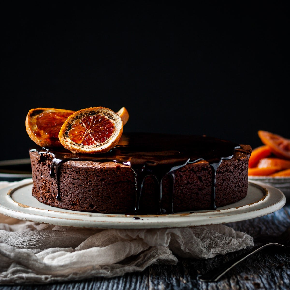 Blood orange chocolate cake on a cake tray with orange slices.