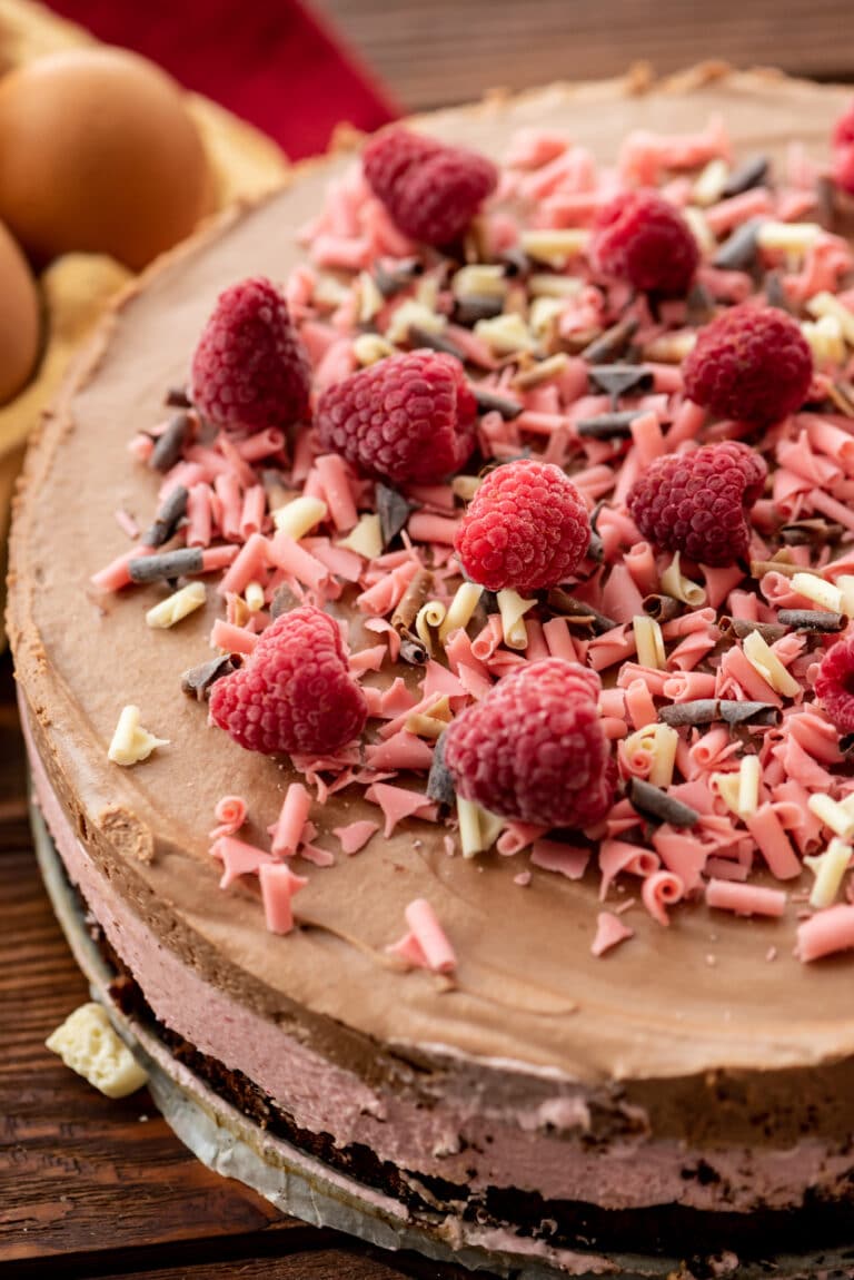 Chocolate raspberry mousse cake with white chocolate swirls and raspberries.