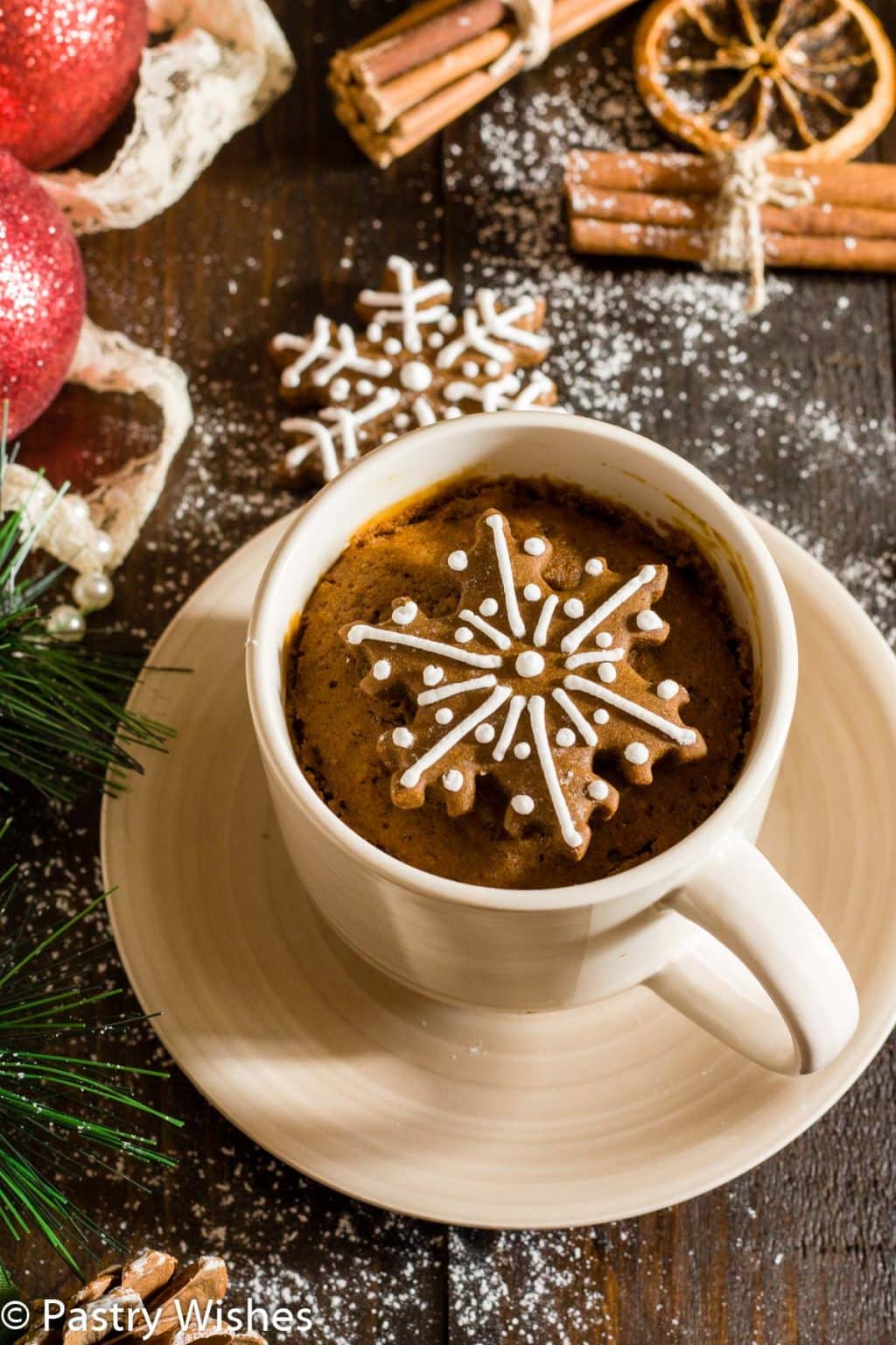 Gingerbread mug cake in a mug on a saucer and a cookie.