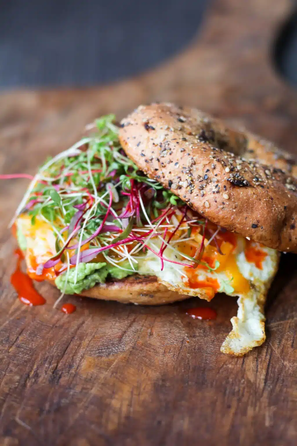 Hearty brunch bagel sandwich on a wooden cutting board.