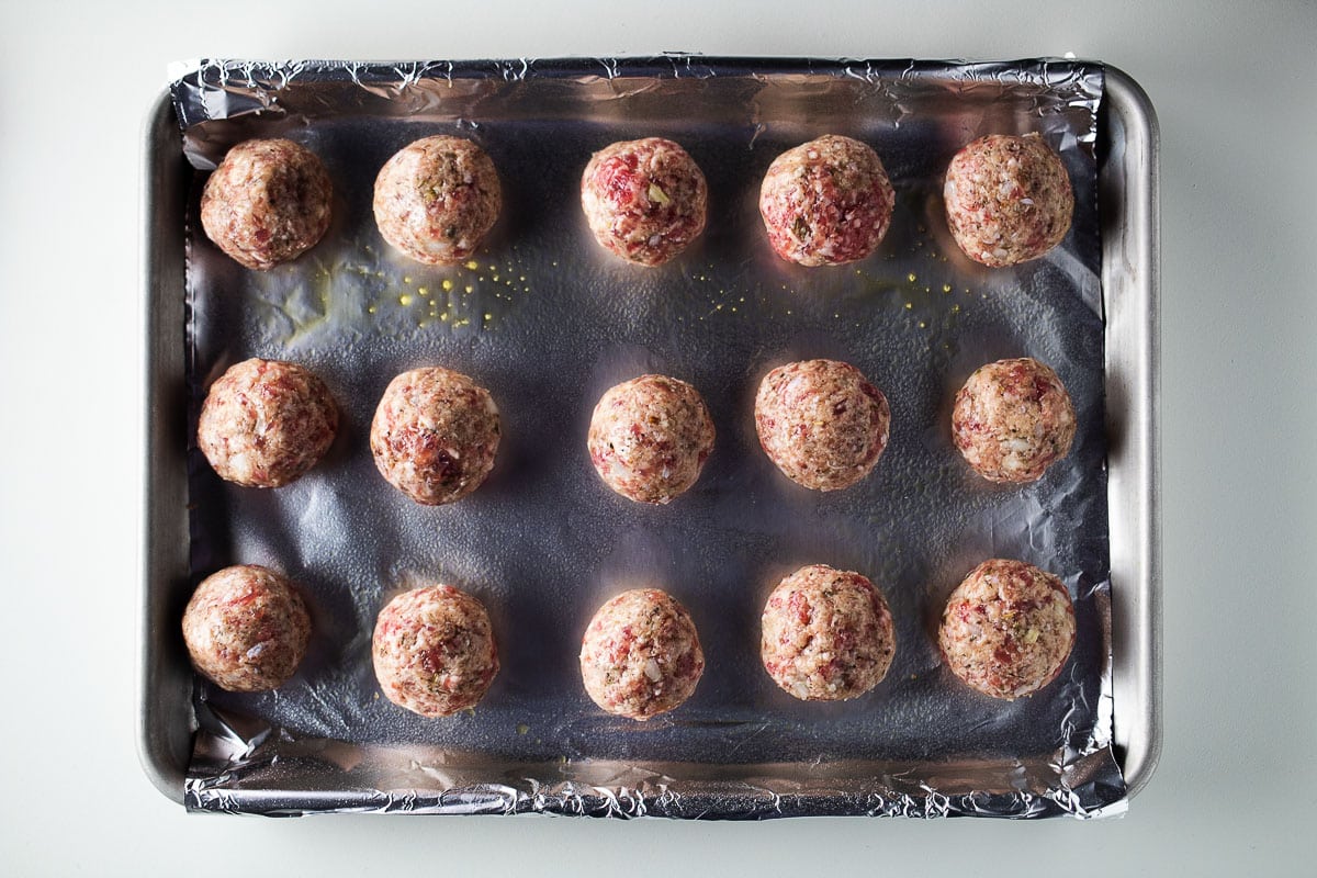 Low carb keto meatballs on a aluminum foil lined baking pan.