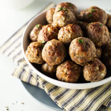 Turkey and sausage meatballs in white bowl on a striped dish cloth.