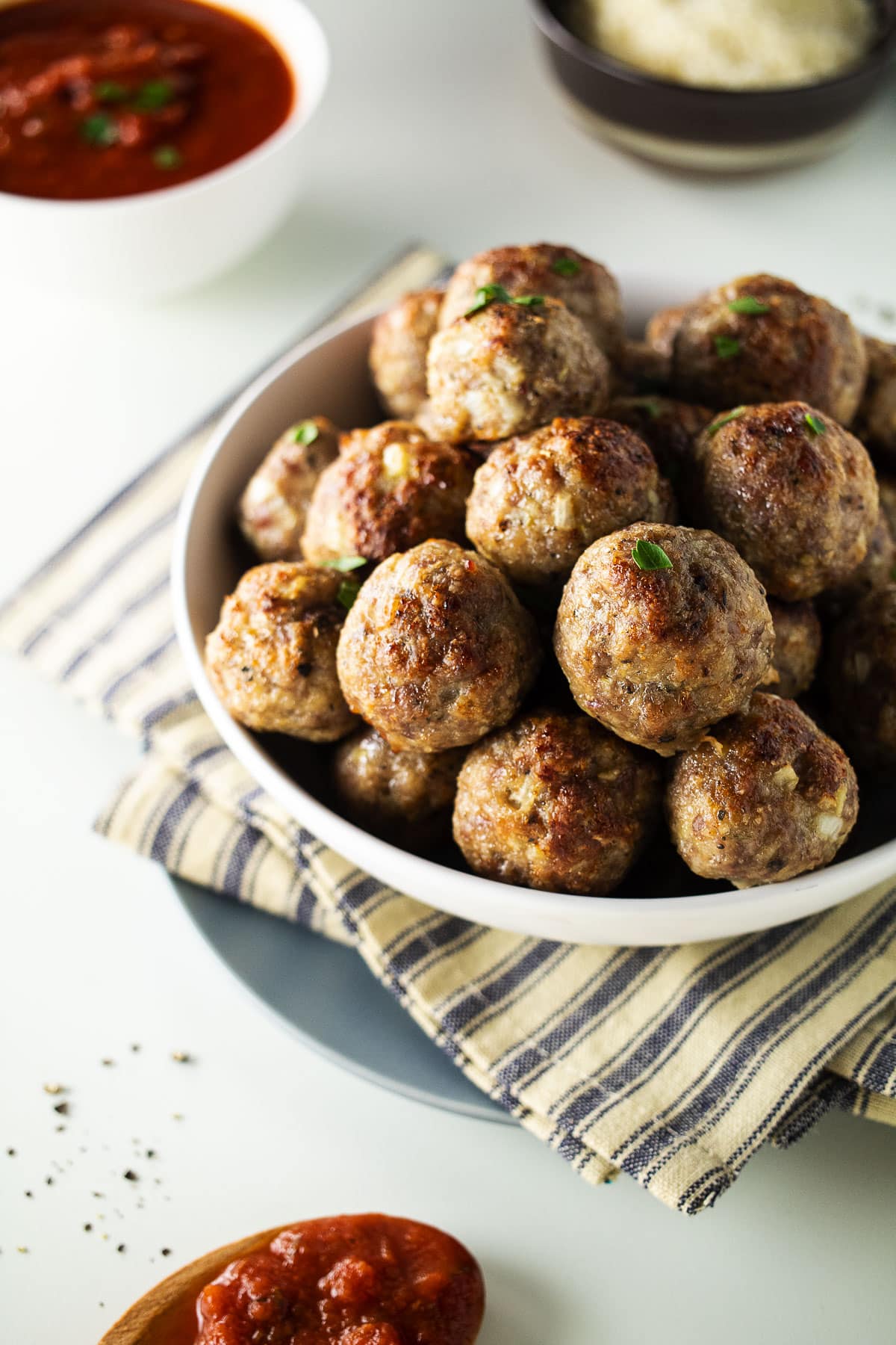 Turkey and sausage meatballs in white bowl on a striped dish cloth.