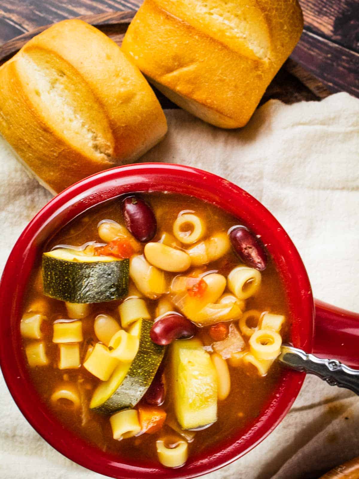 Slow cooker minestrone soup in a red bowl.