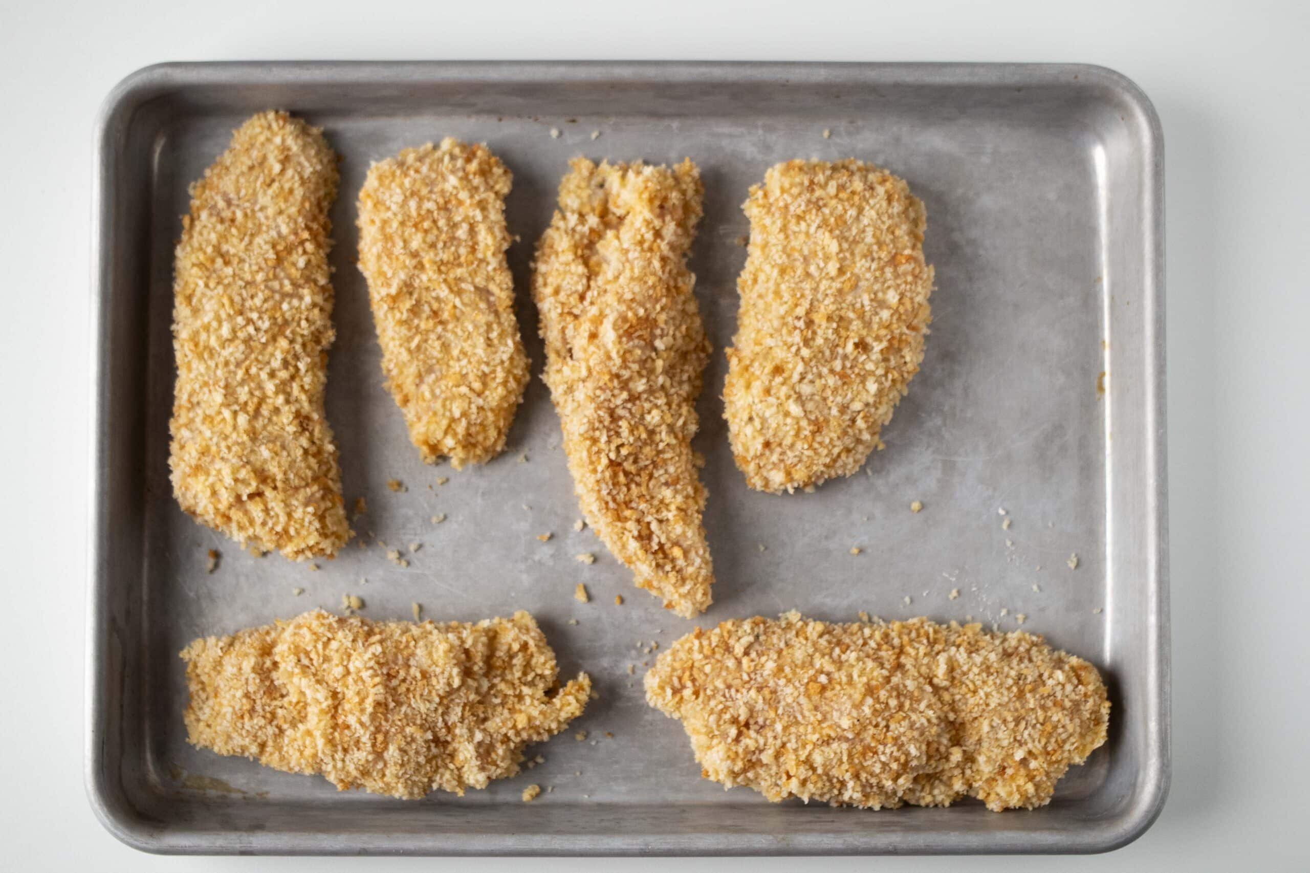 Chicken breast strips uncooked on a tray.