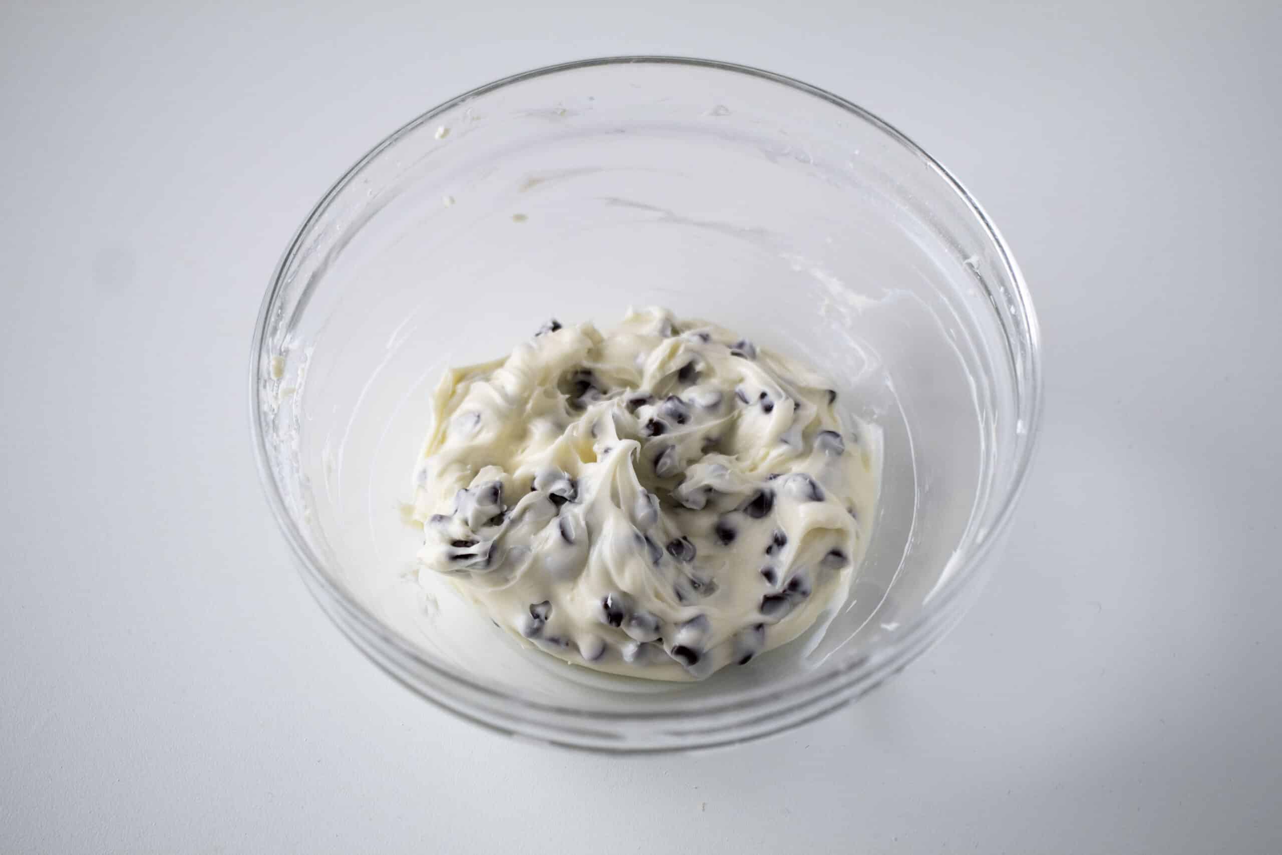 Cream cheese and chocolate chip mixture in a clear bowl.