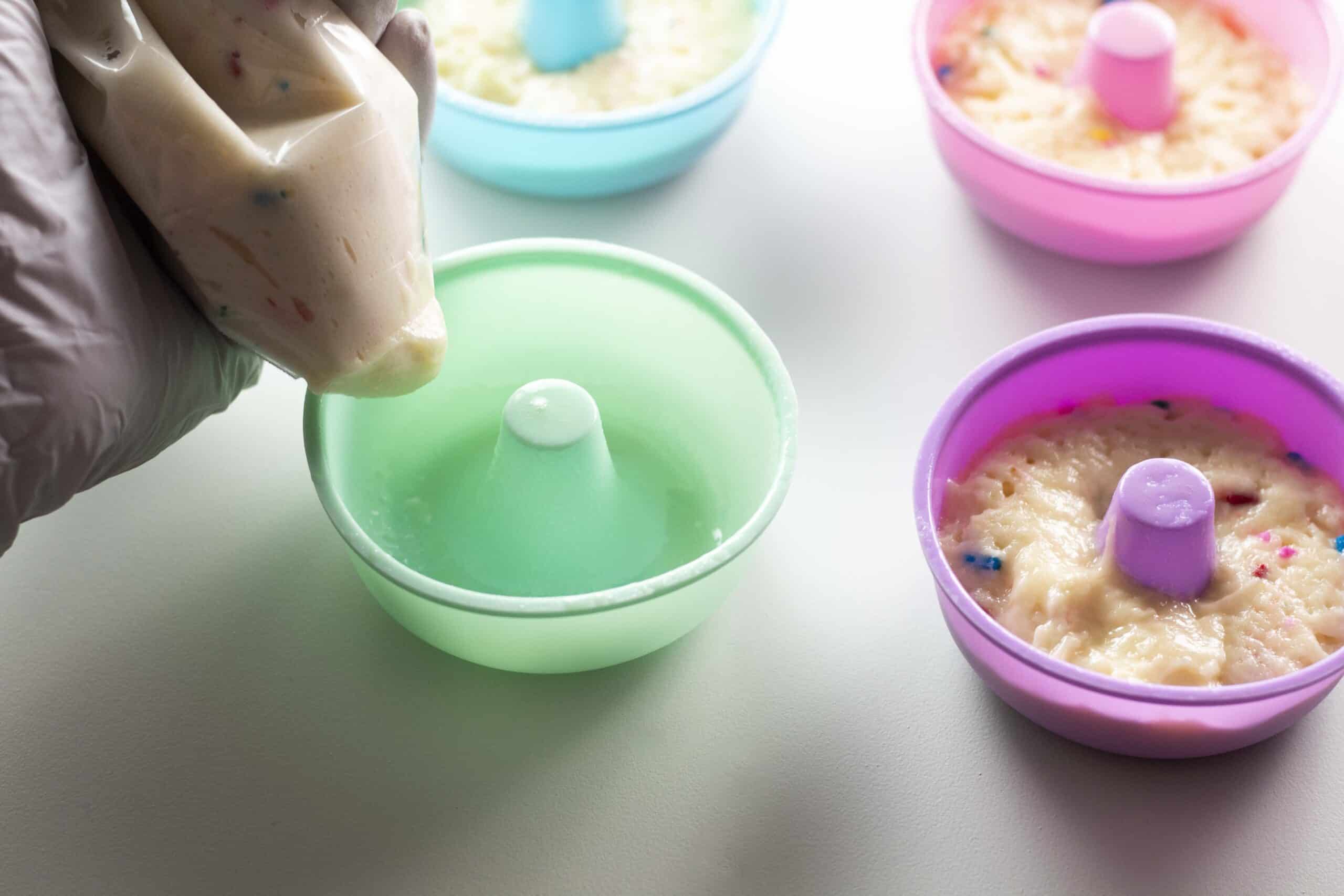 Putting donut batter in donut molds.