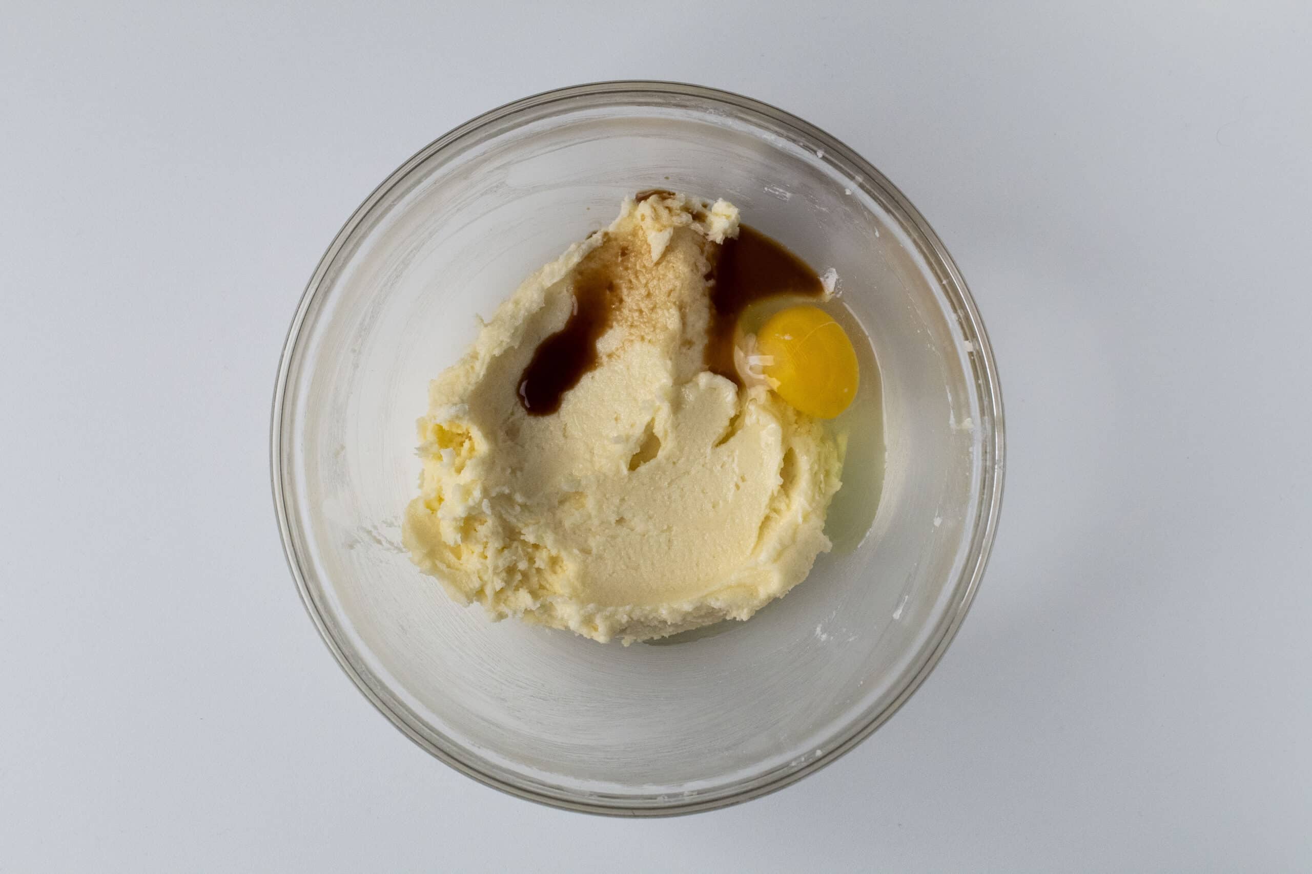 Creamed sugar and butter with egg and vanilla in a clear bowl.