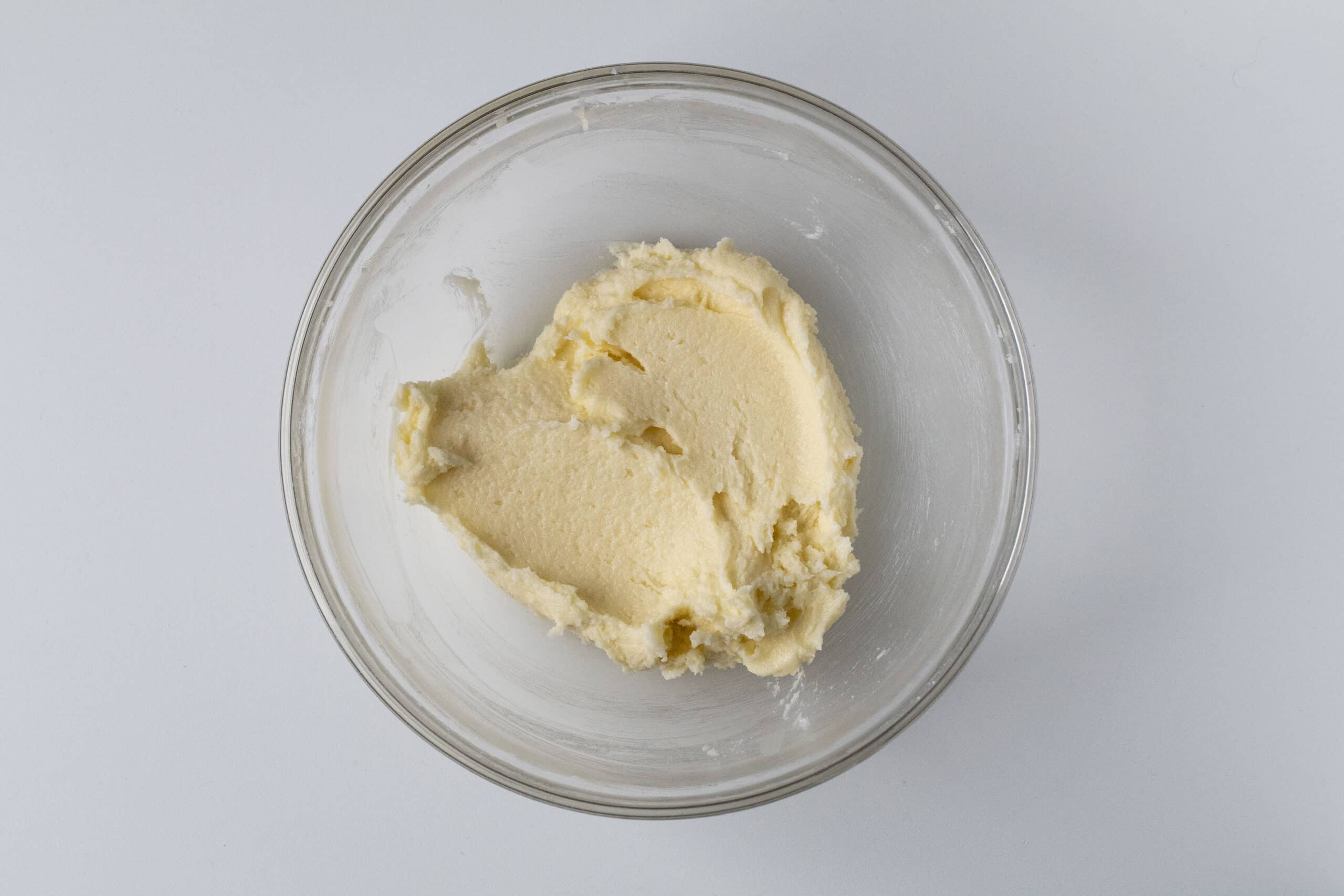 Creamed sugar and butter for sugar cookie in a clear bowl.