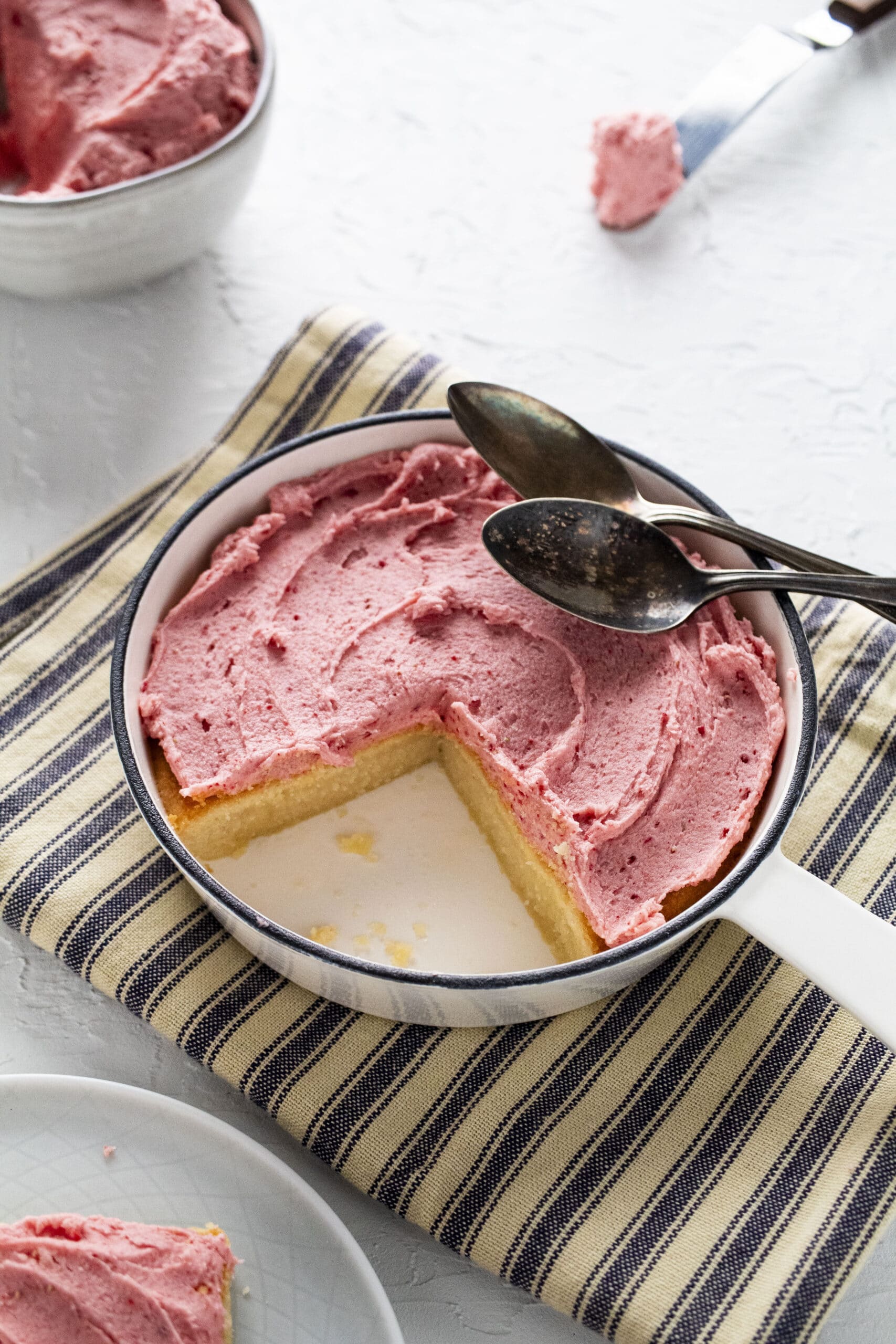 Sugar cookie topped with strawberry frosting in a cast iron pan.