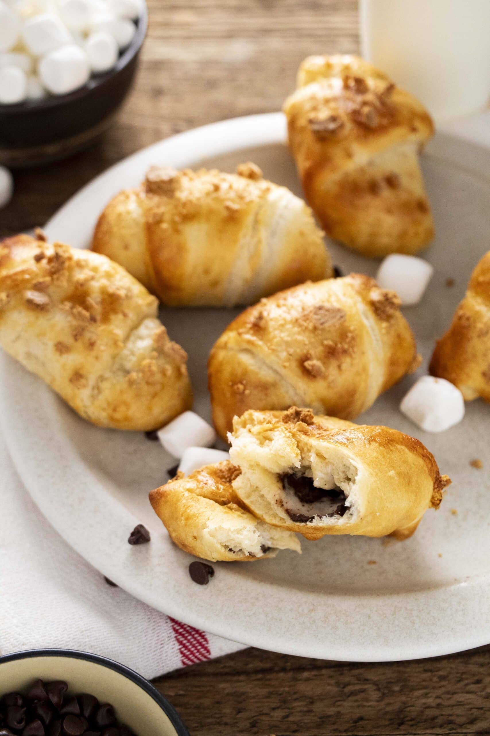 Air fryer s'mores crescent rolls on a plate with marshmallows and mini chocolate chips.