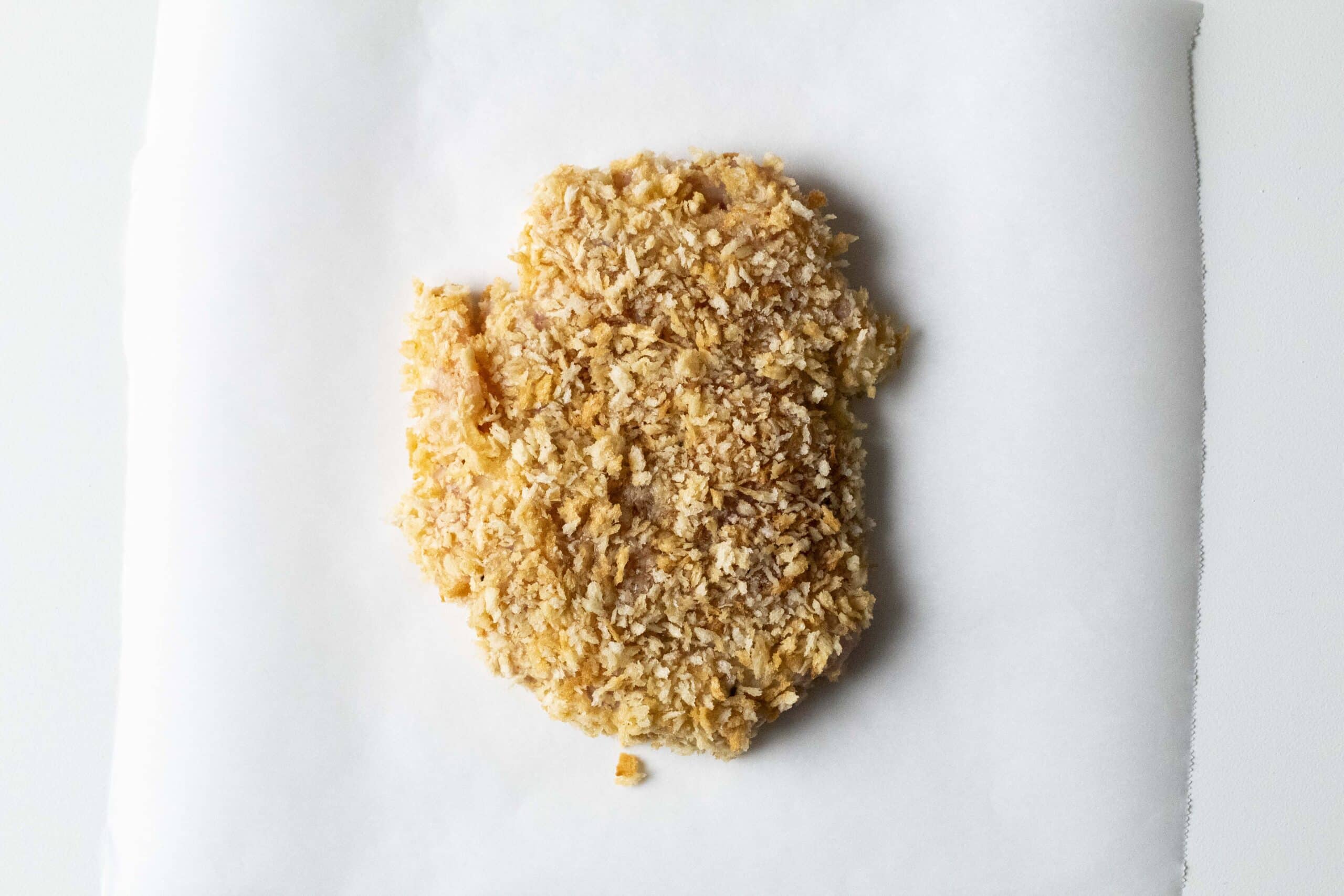 Breaded chicken thigh on a white background.