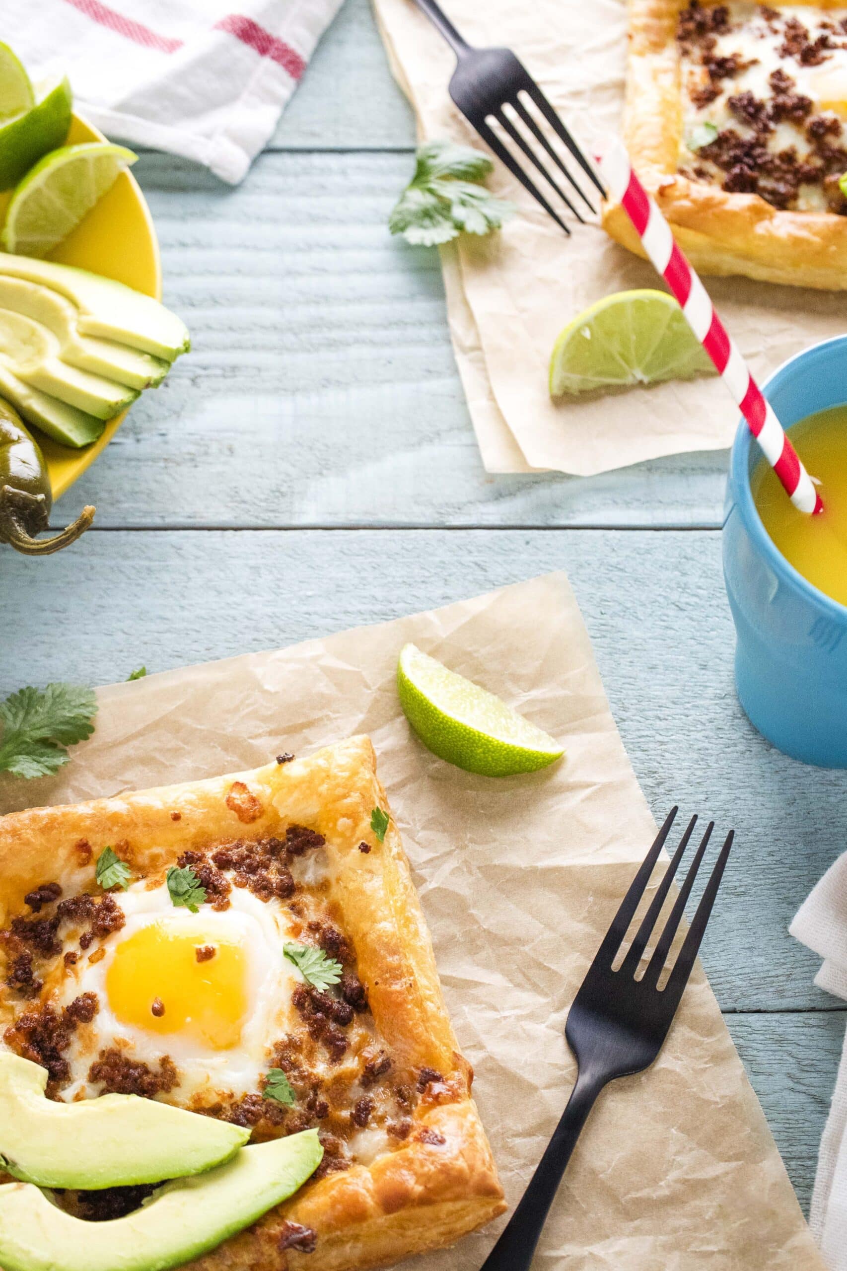 Air Fryer Mexican Breakfast Pizza on parchment paper with toppings, cutlery and orange juice.