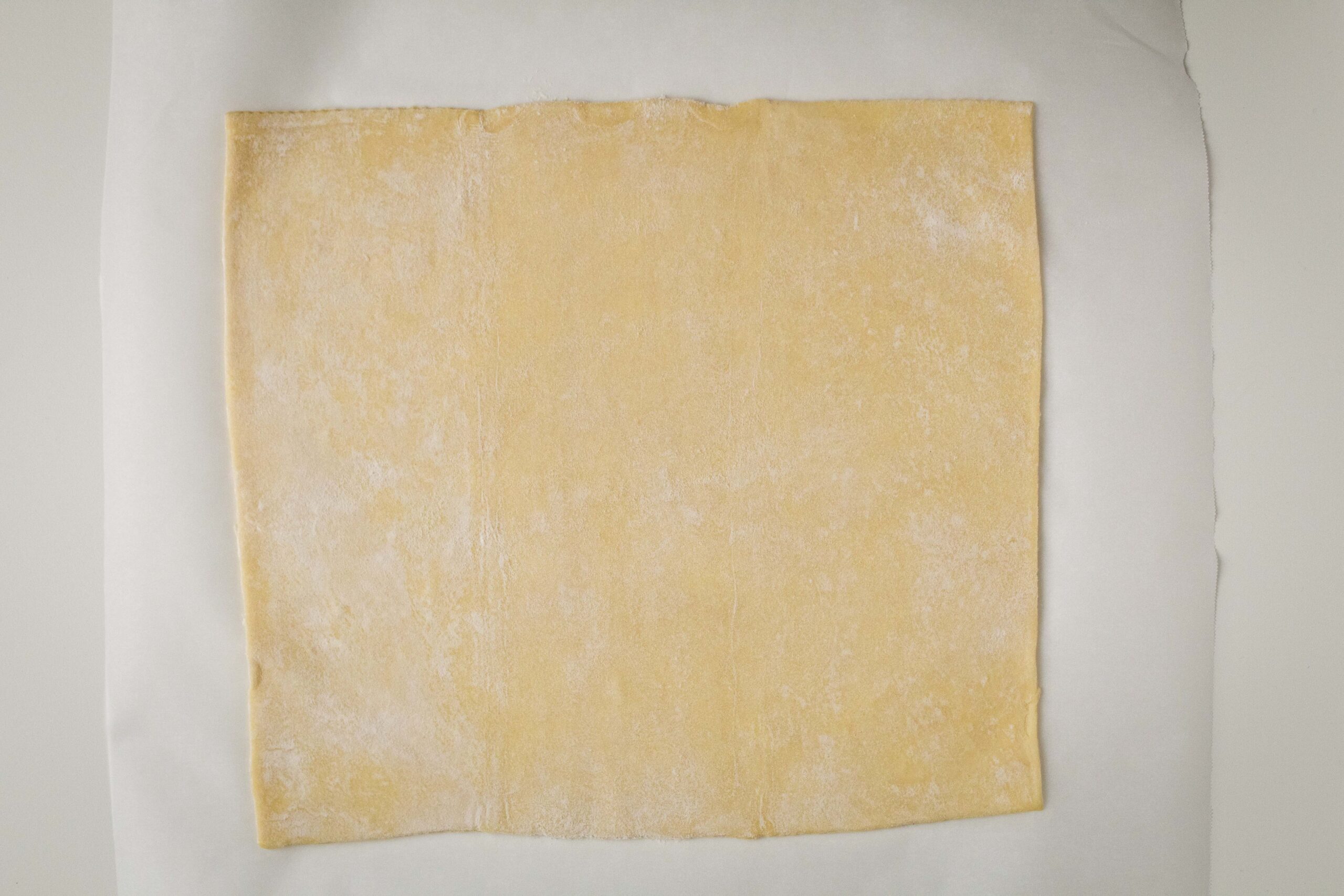 Puff pastry rolled out on a sheet of parchment paper.