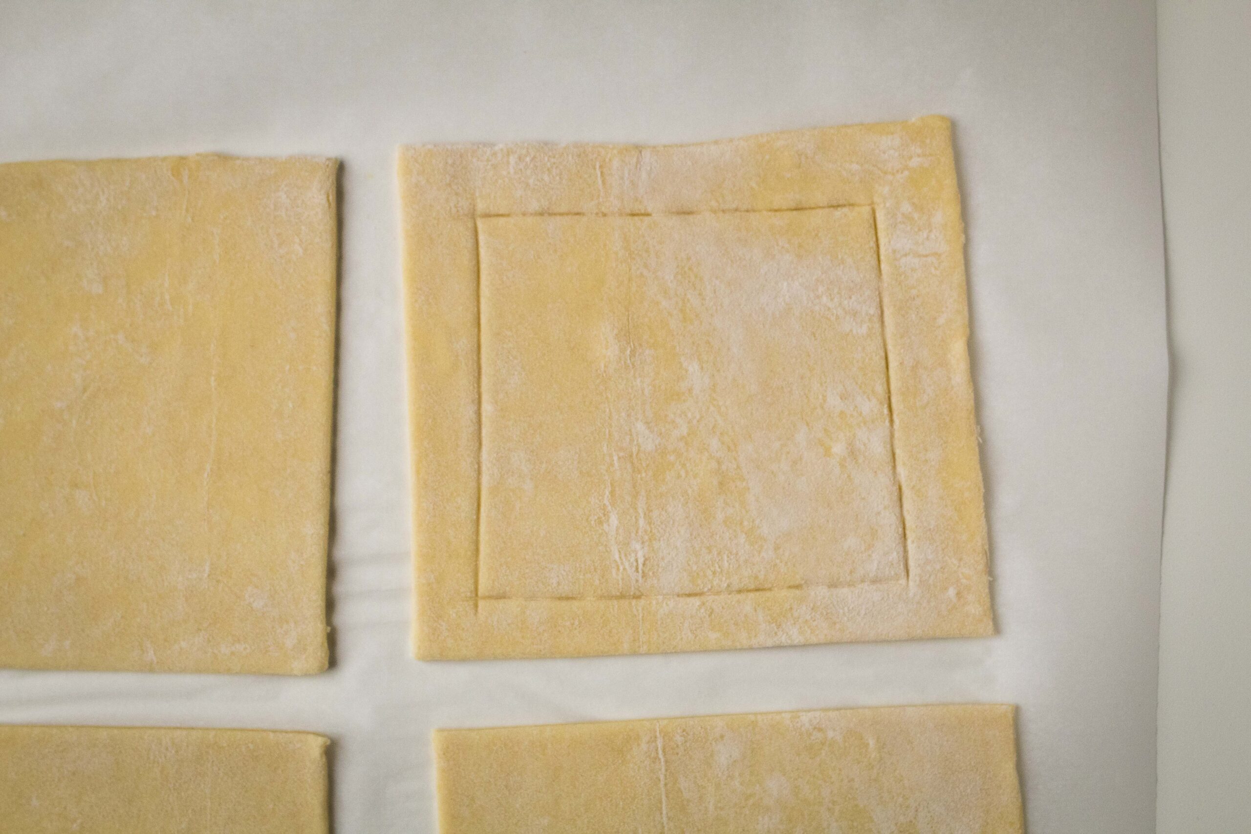 Puff pastry cut into four pieces with a border scored into it.