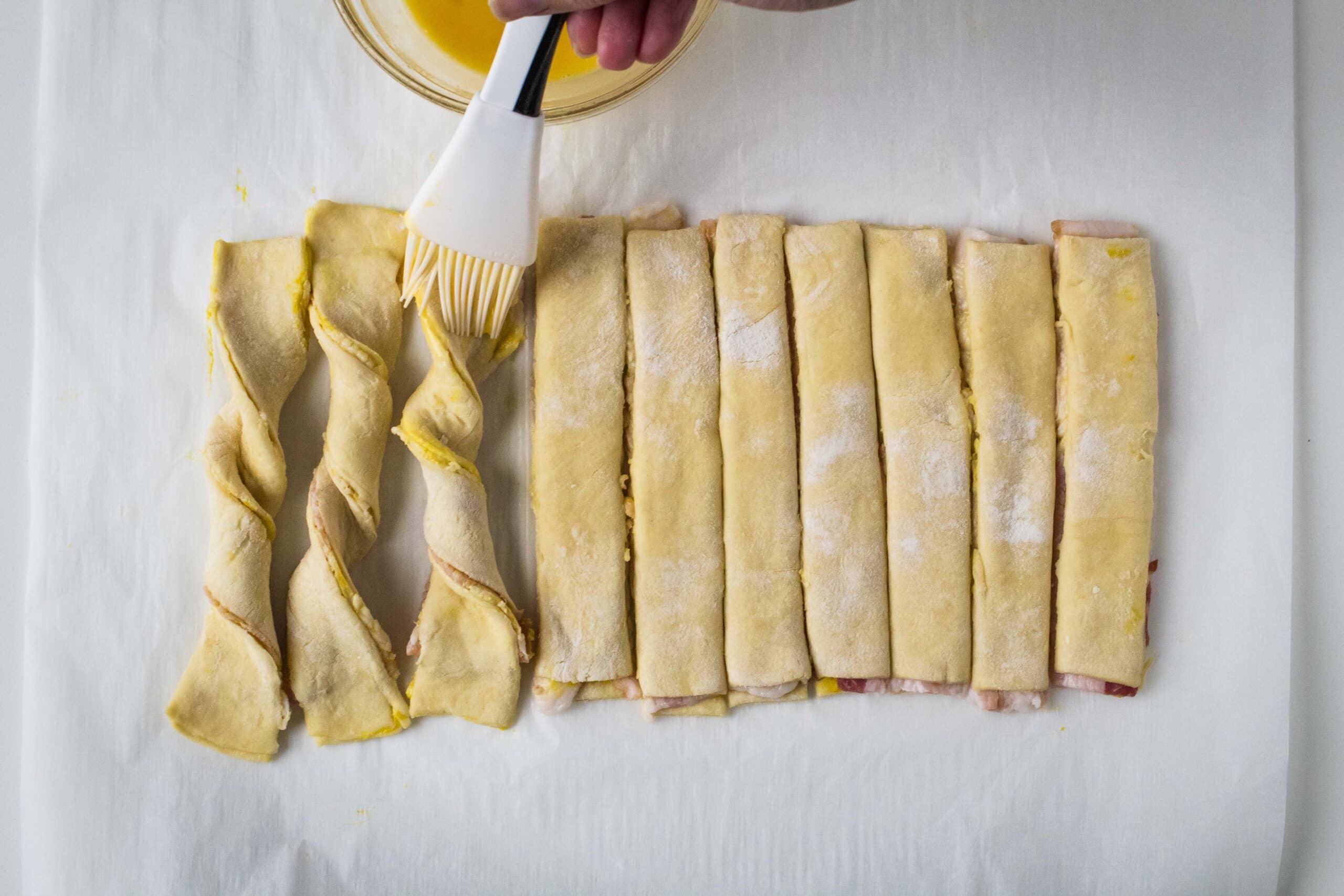 Uncooked puff pastry bacon twists with egg wash.