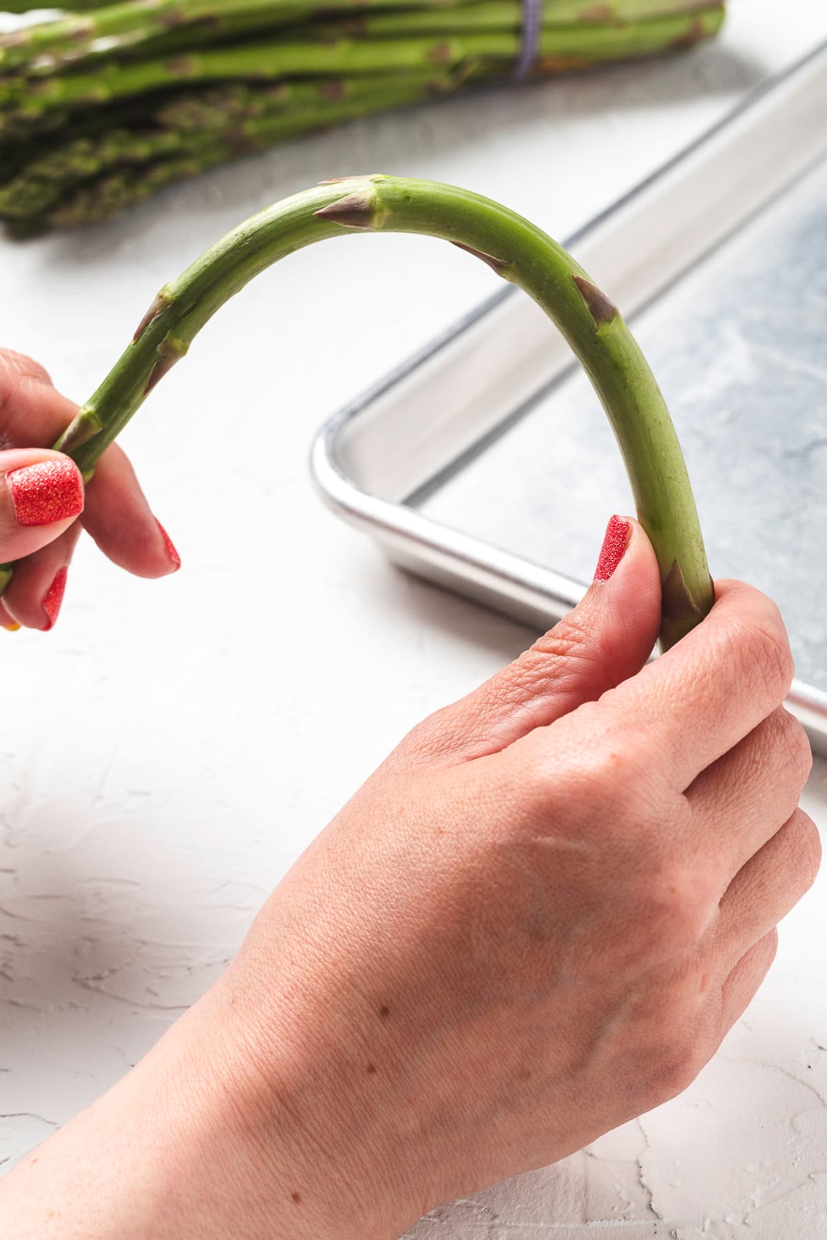 Hands bending asparagus spear.