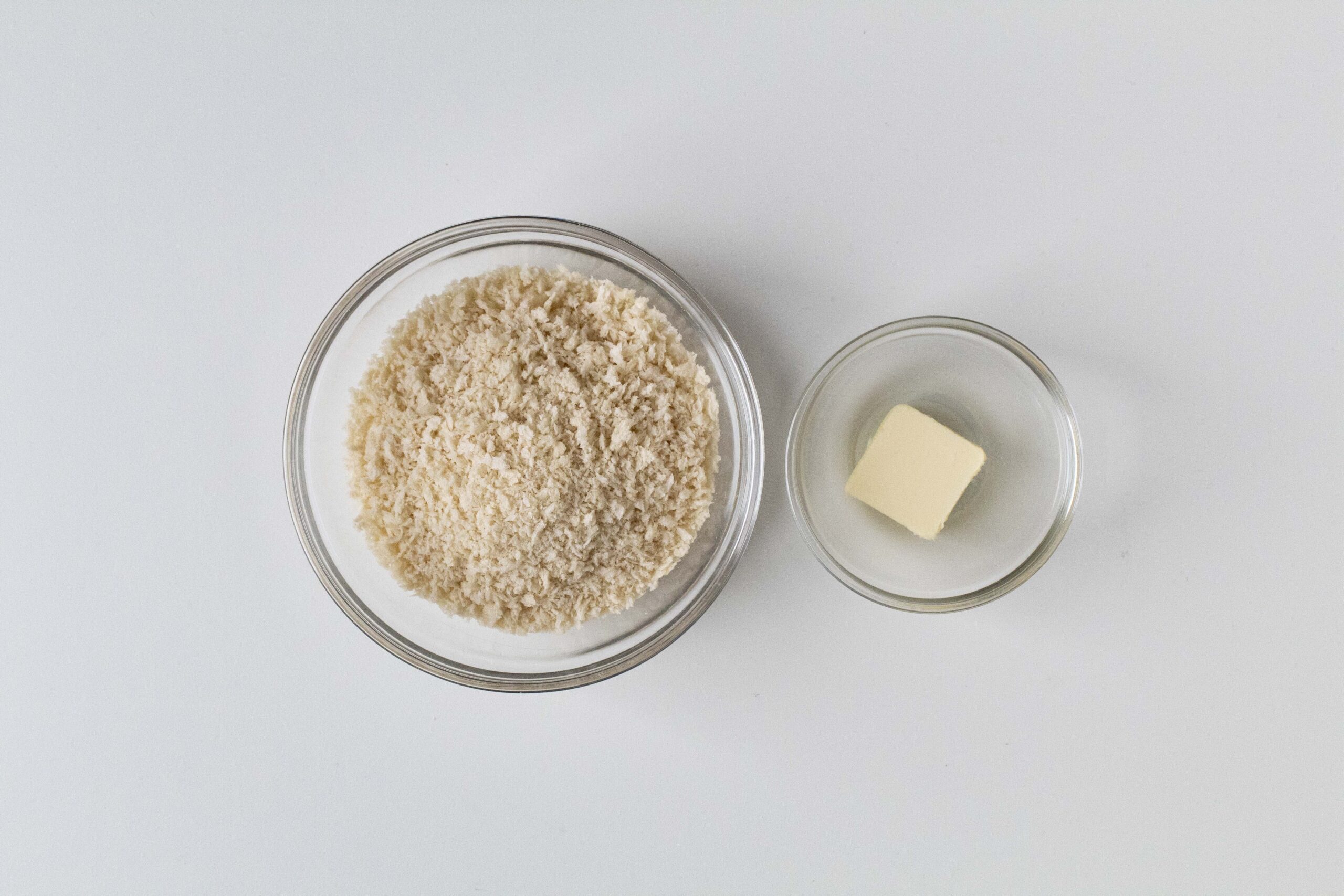 Panko breadcrumbs and butter in clear bowls.