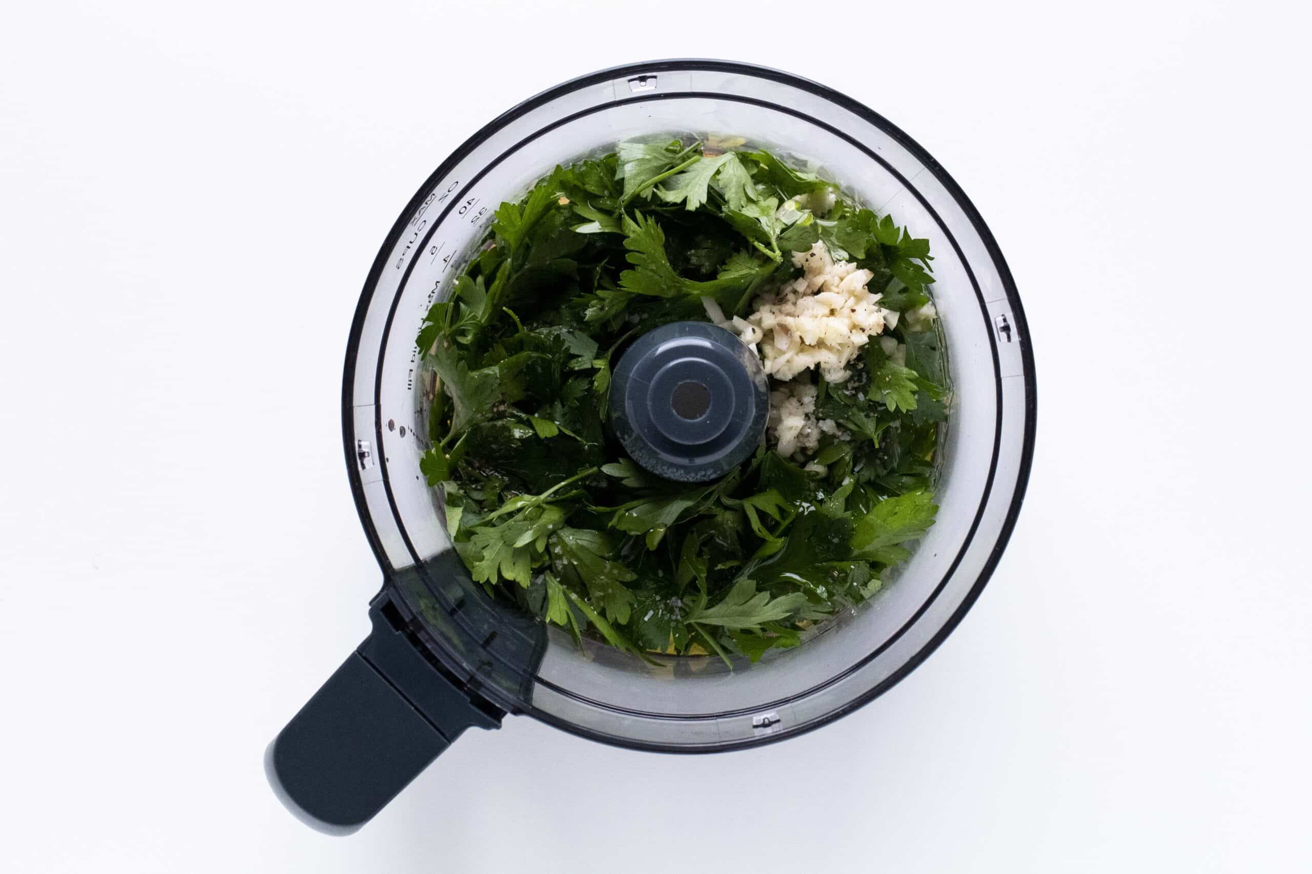 Ingredients for chimichurri in a food processor bowl.