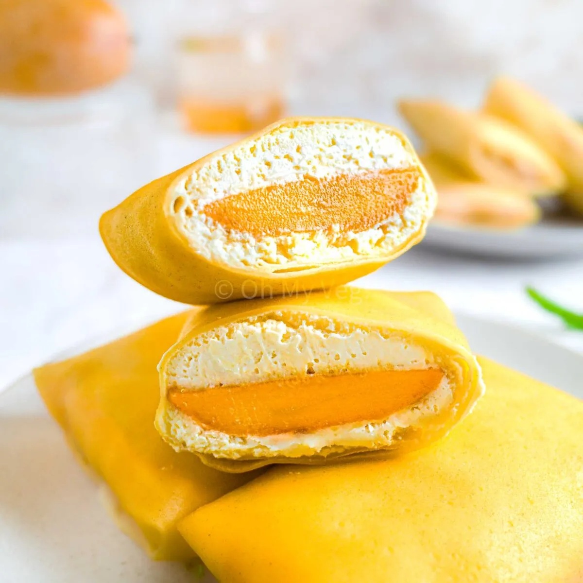 Mango pancakes with a thin crepe-like exterior, filled with mango slices and whipped cream.