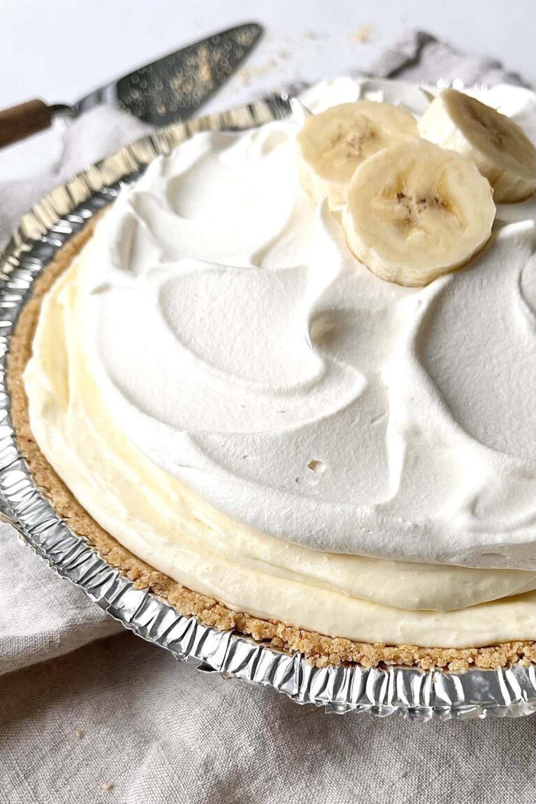 Banana cream pie in a graham cracker crust, topped with whipped cream and banana slices.