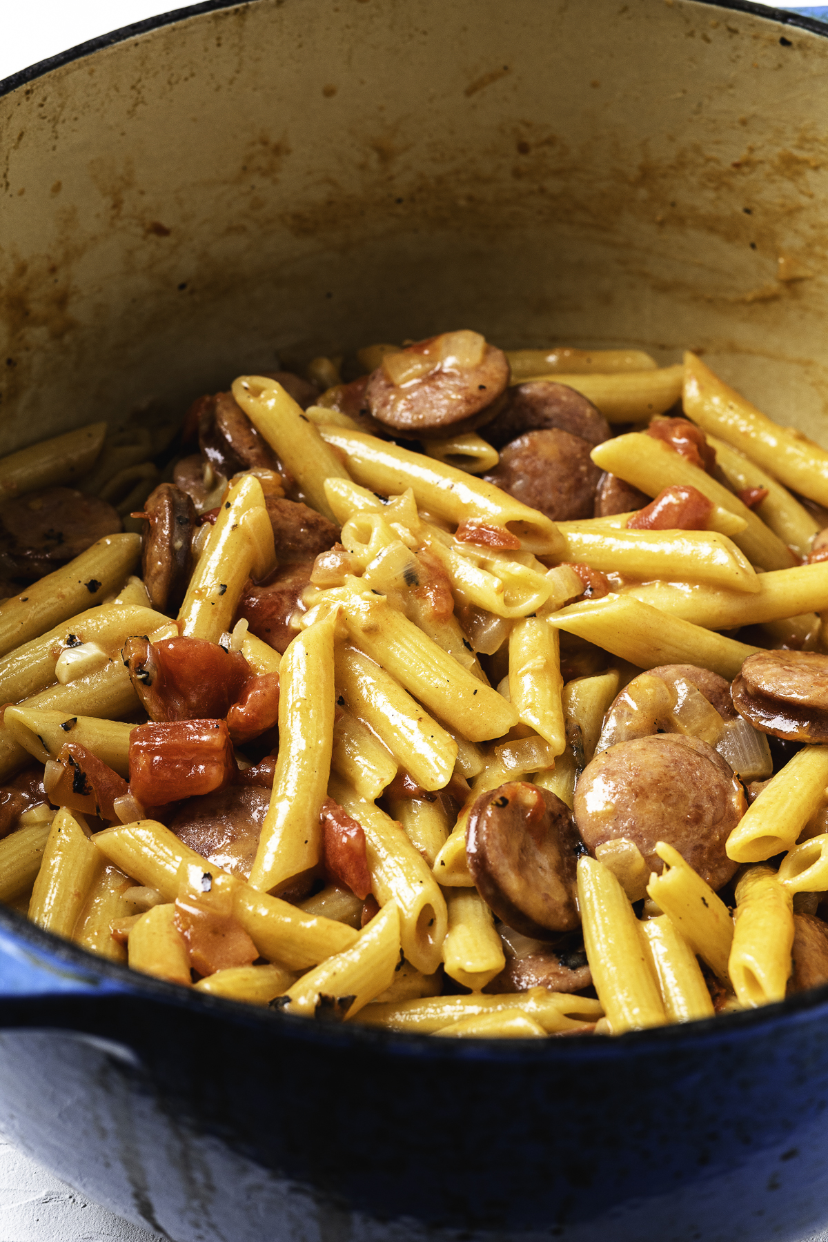 Kielbasa, pasta, and tomatoes fully mixed and cooked together in a creamy sauce.