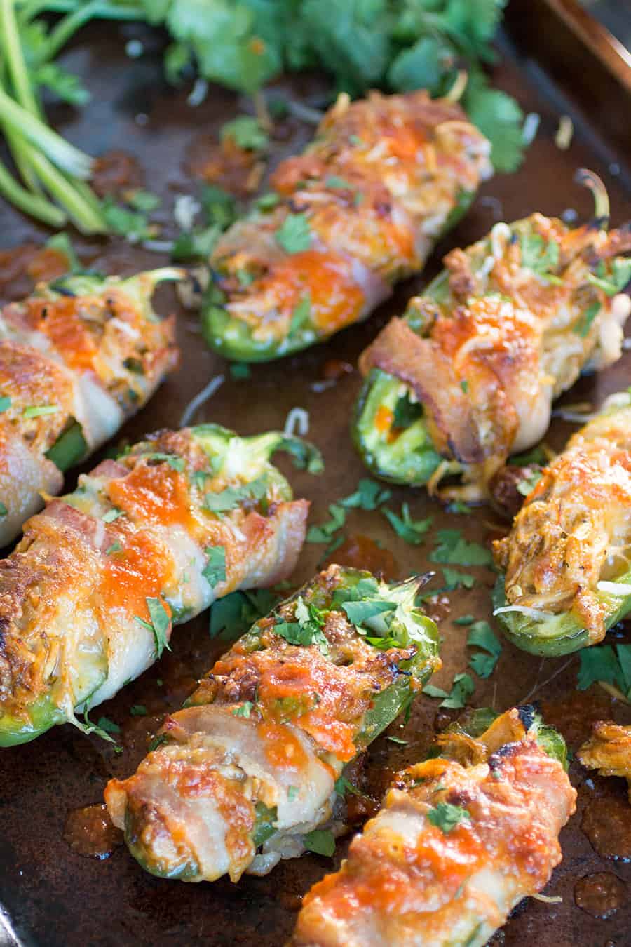 Jalapeño halves filled with shredded chicken and cheese, wrapped in bacon and baked.