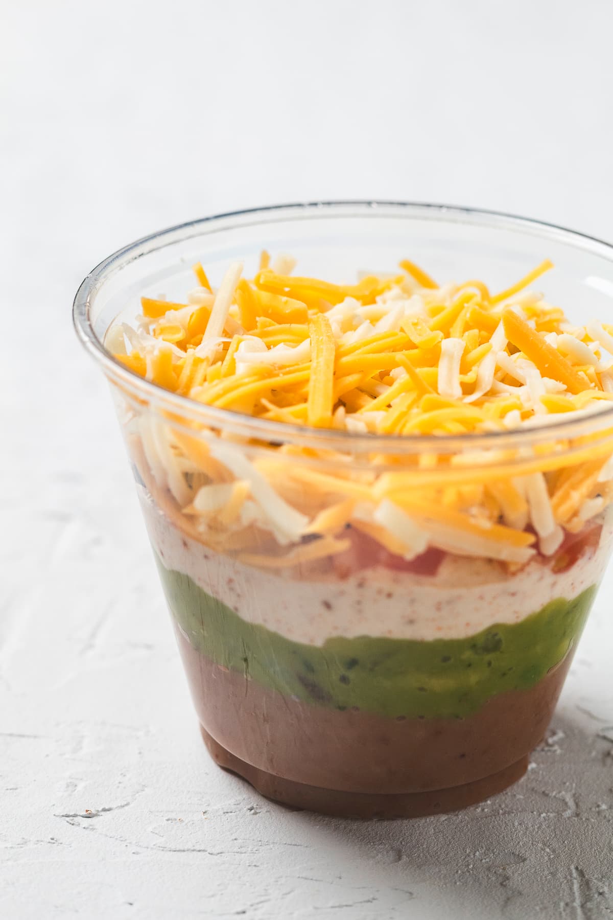 Completed individual 7-layer taco dip cup on a white background with all layers.
