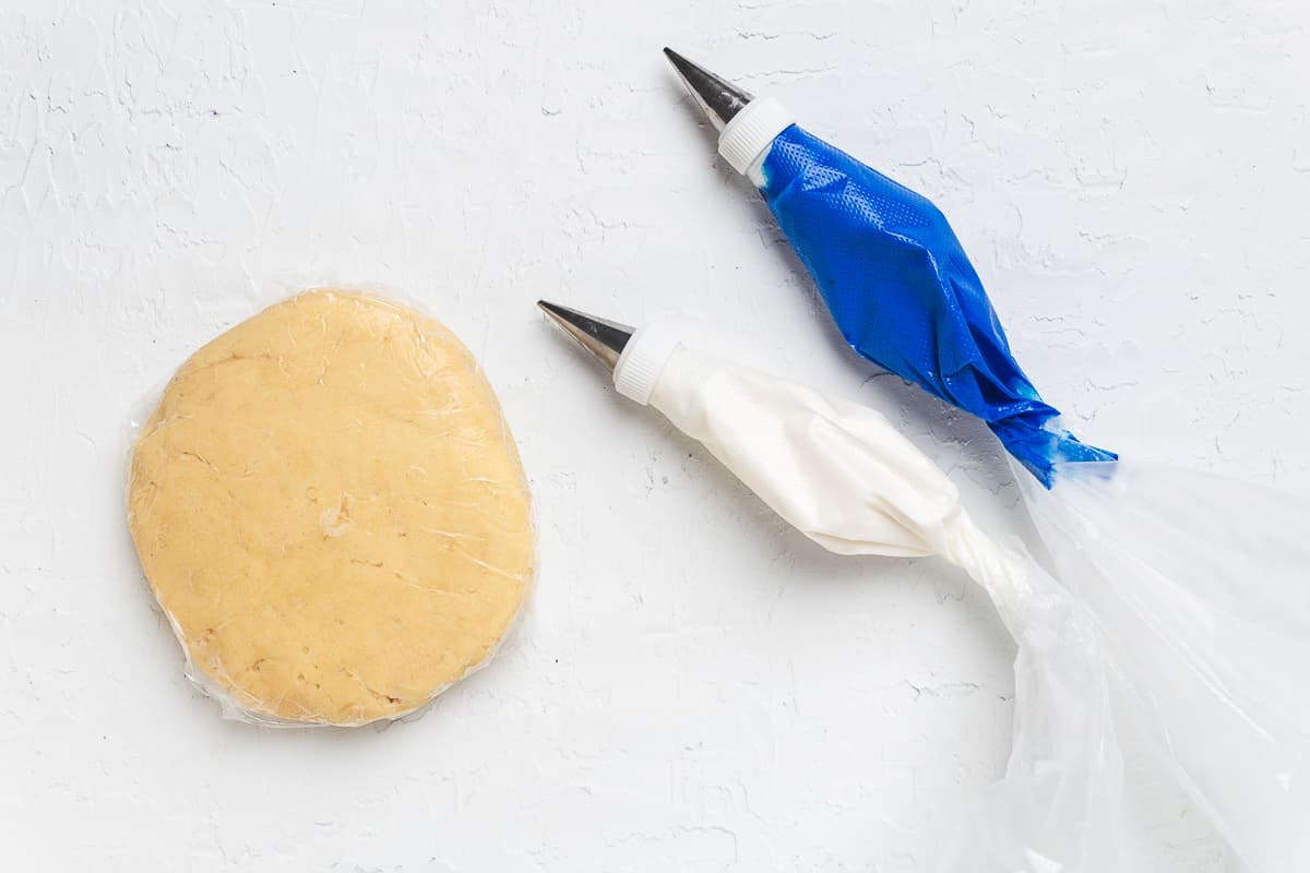 Cookie dough with white and blue royal icing on a white background.