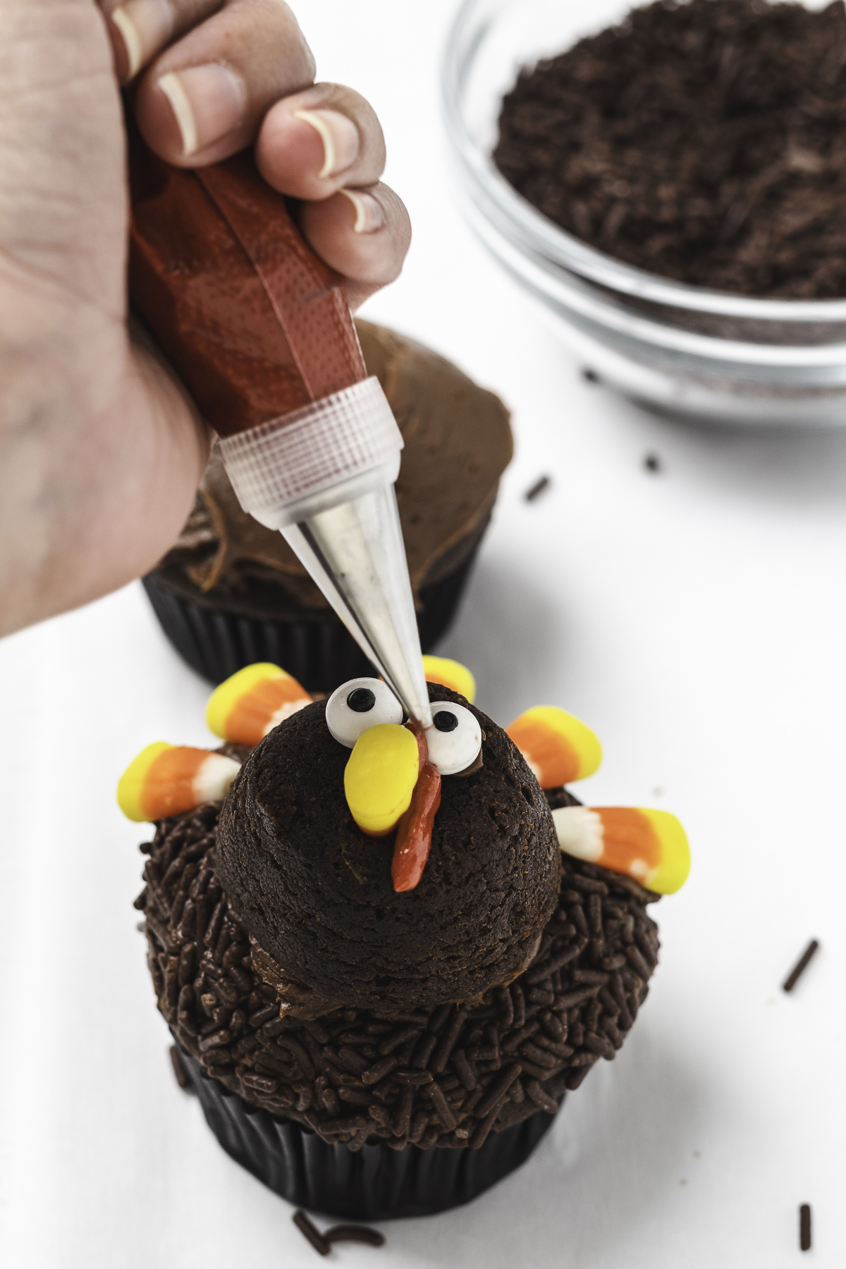 Adding red wattle to face of turkey cupcake.