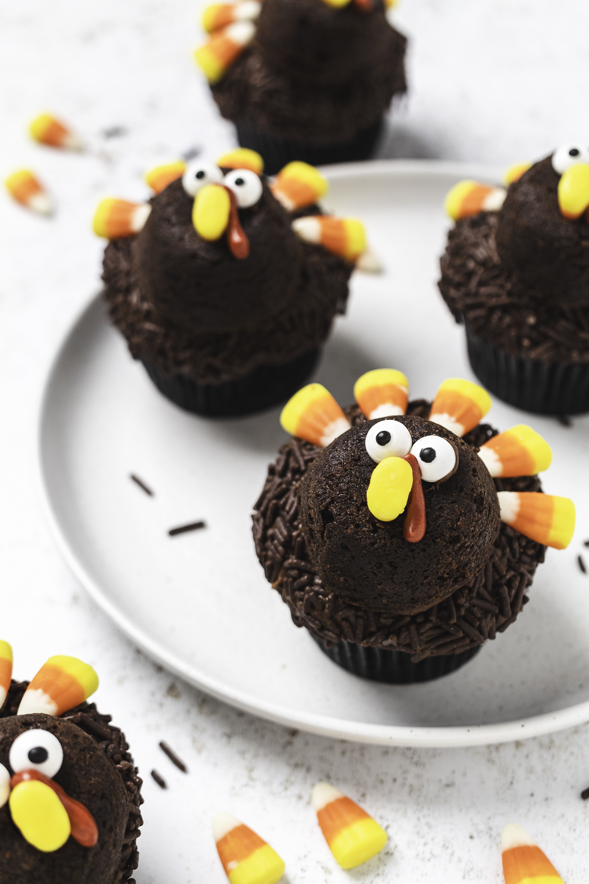 Chocolate Thanksgiving turkey cupcakes arranged on a light colored plate.