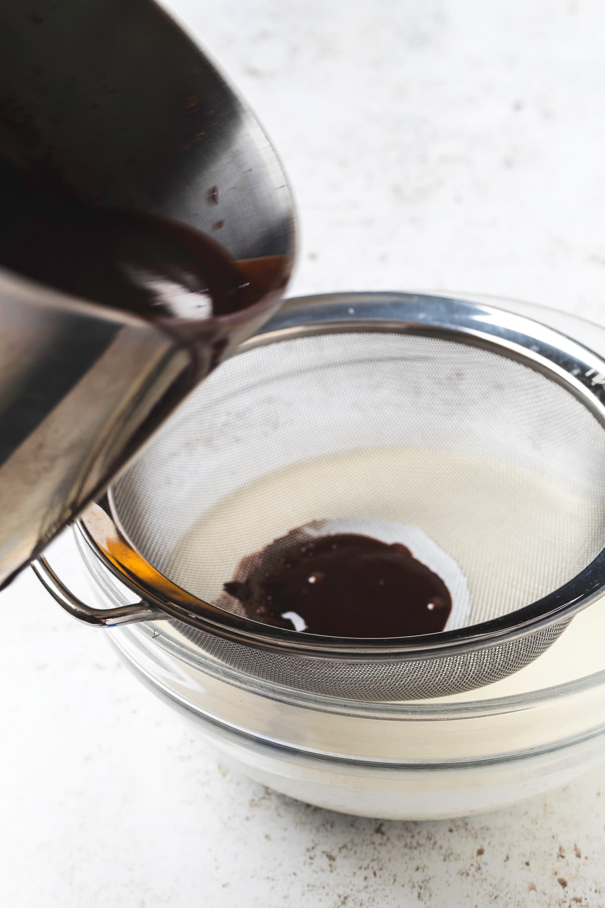 Straining chocolate mixture into heavy cream.