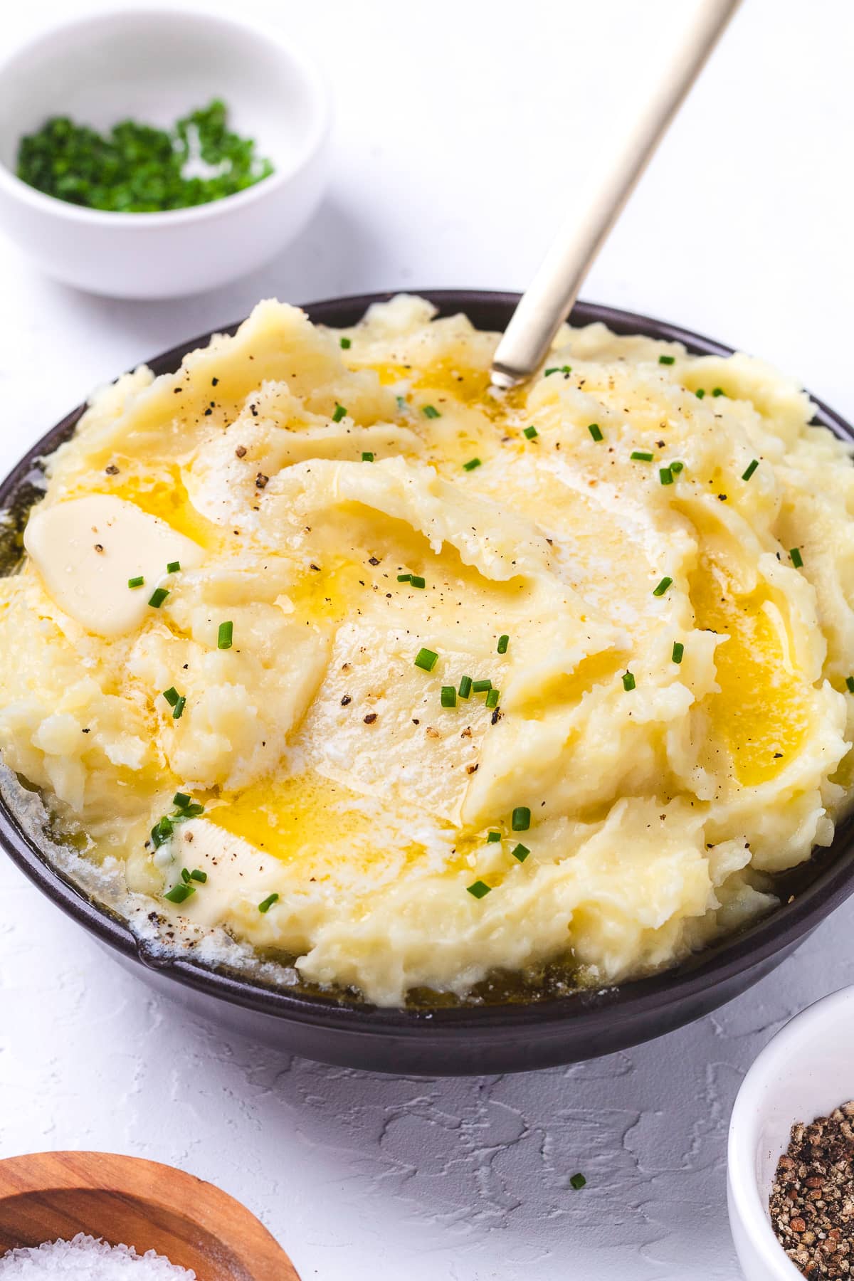 Buttery mashed potatoes in a dark brown bowl.