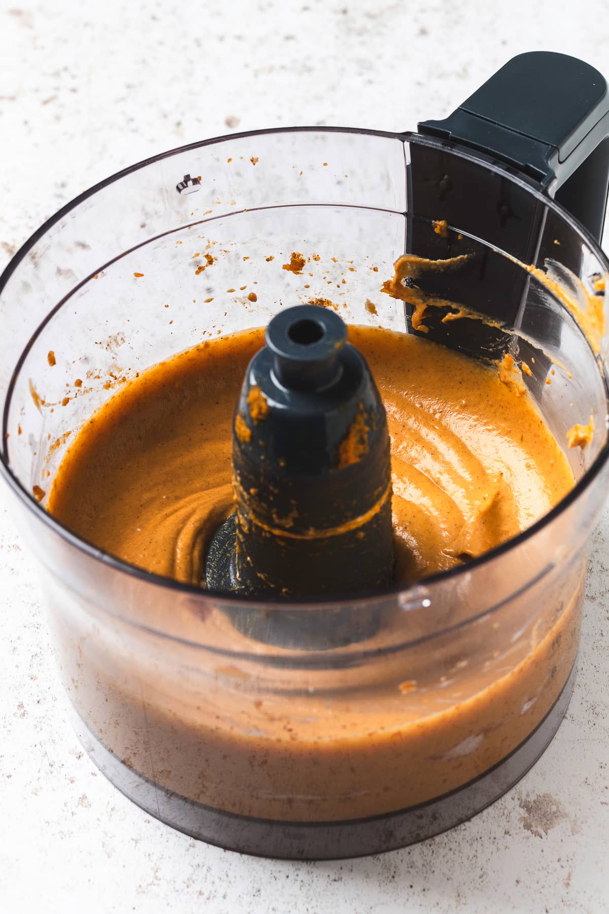 Blended ingredients for pumpkin spice latte dip in a food processor bowl.