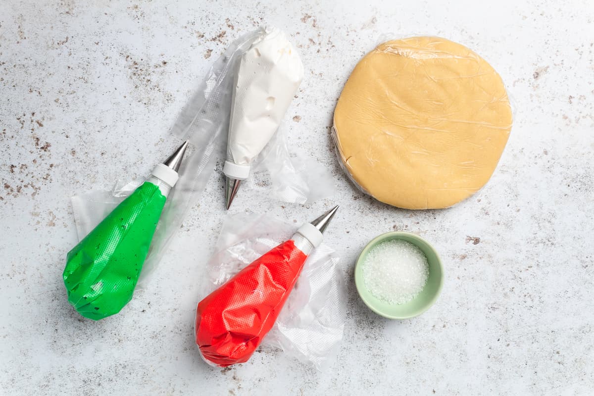 Ingredients for making Christmas sugar cookies arranged on a white surface.