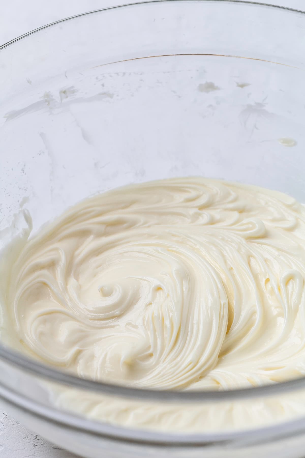 Cream cheese and powdered sugar combined in a clear bowl.