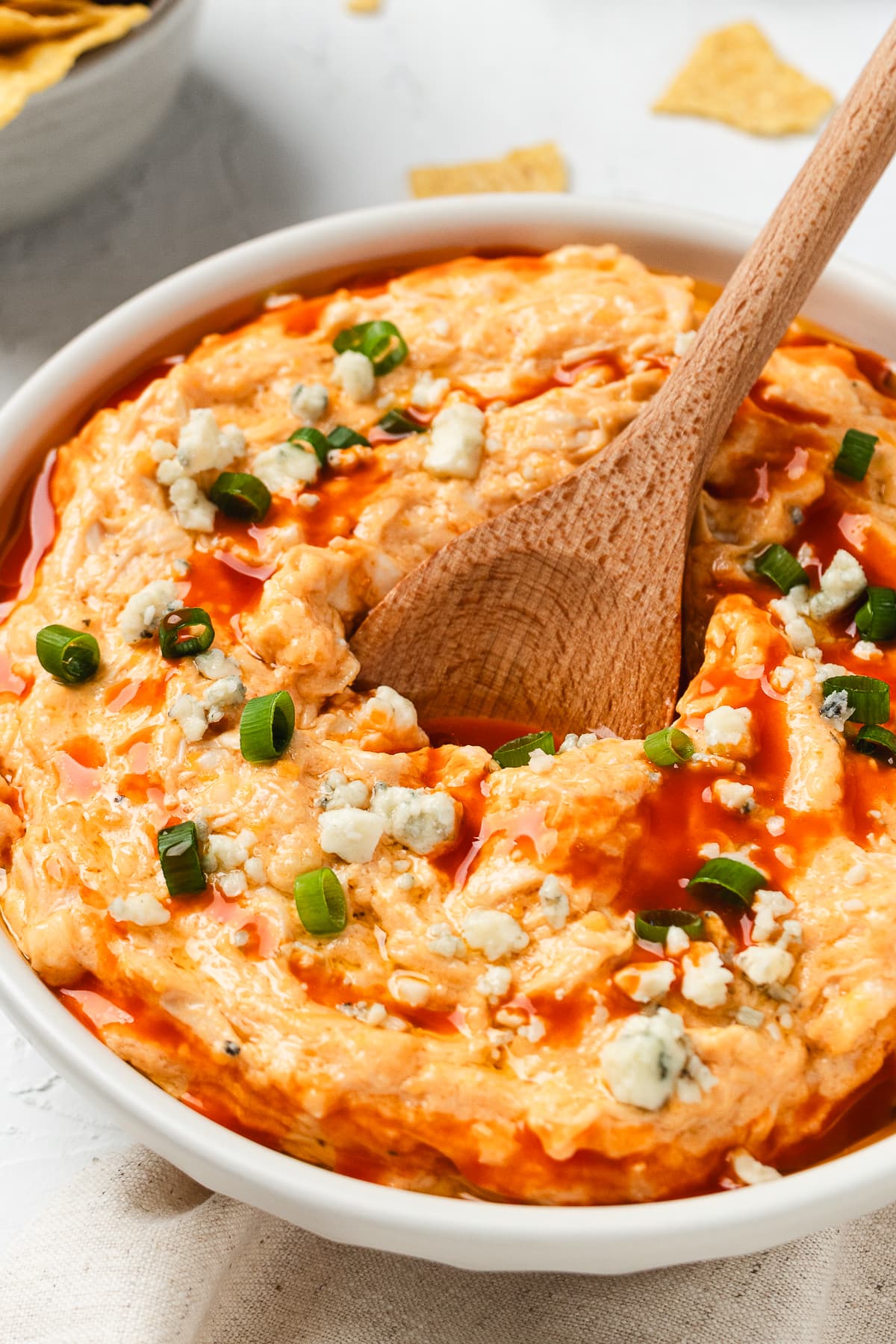 Close-up of creamy crockpot buffalo chicken dip in a light colored bowl.