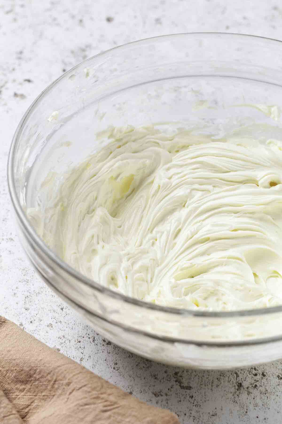Cream cheese and sour cream mixed in a clear bowl.