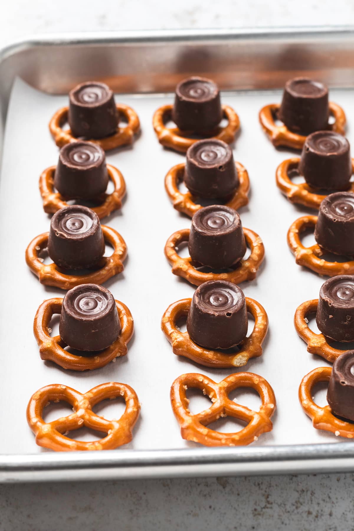 Rolos on top of pretzels on a parchment lined baking sheet.
