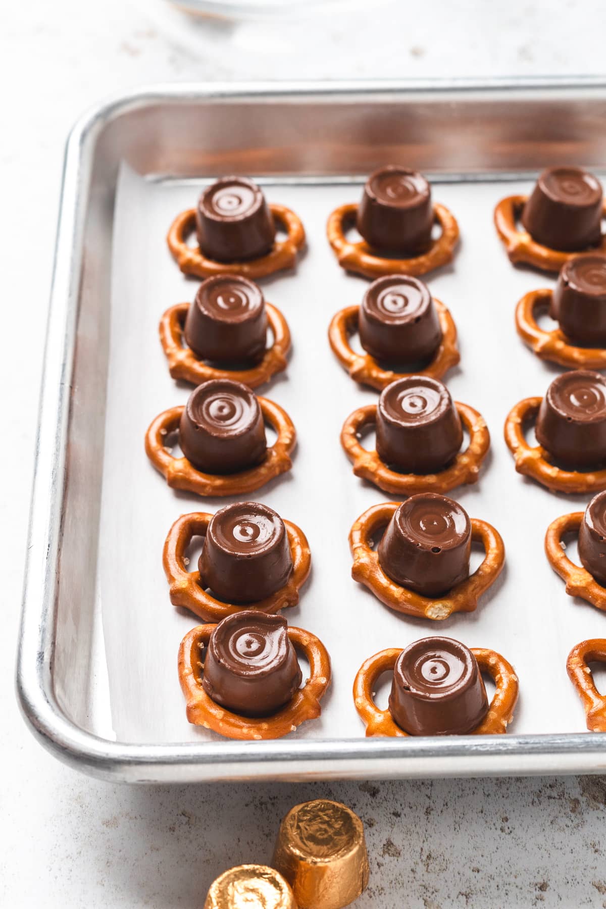 Rolos on pretzels on a parchment lined baking sheet after baking.