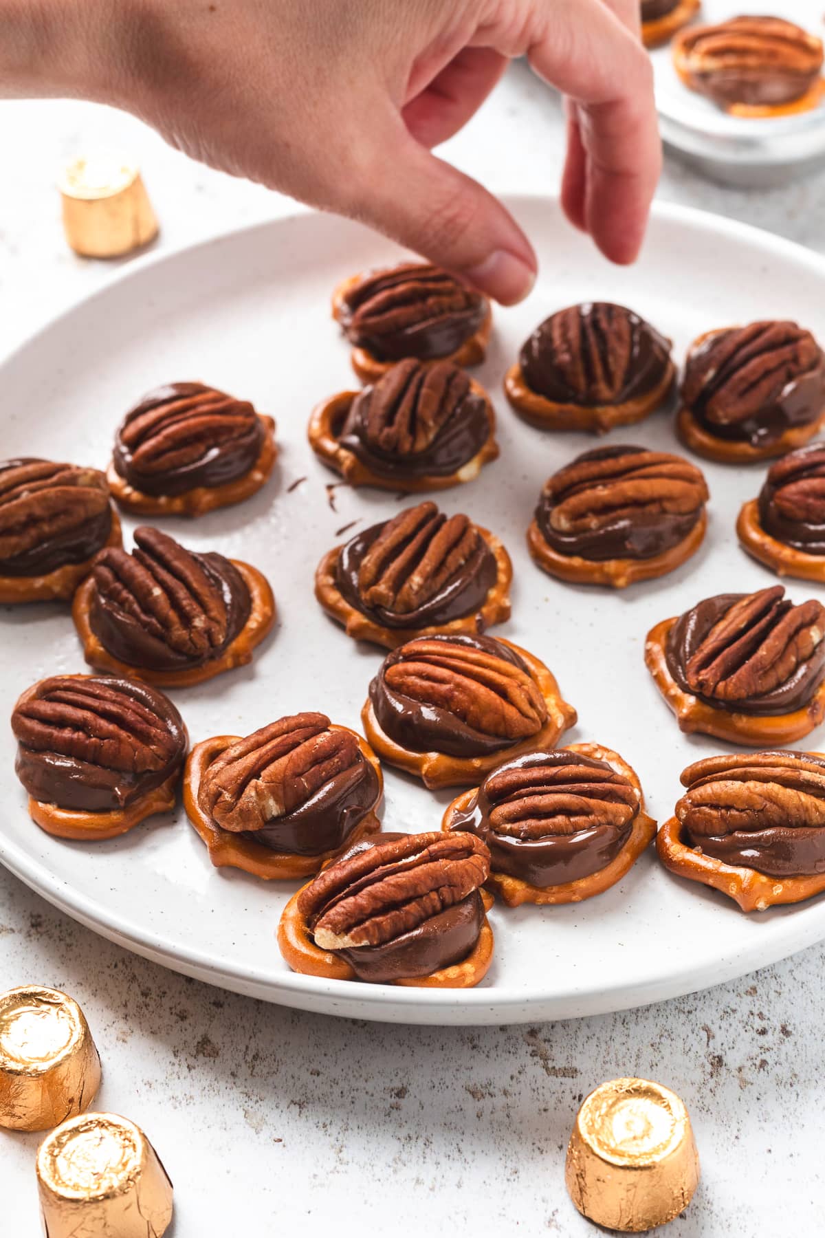 Hand reaching for chocolate caramel pretzels.
