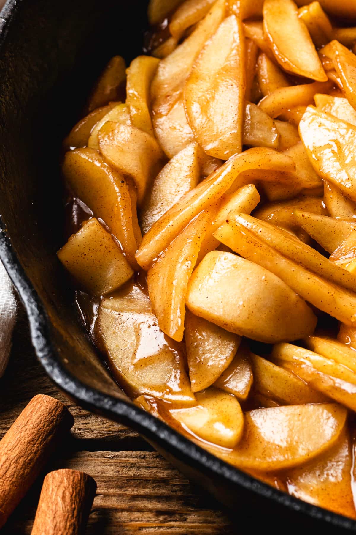 Close-up of warm apple pie filling with cinnamon in a cast iron skillet.