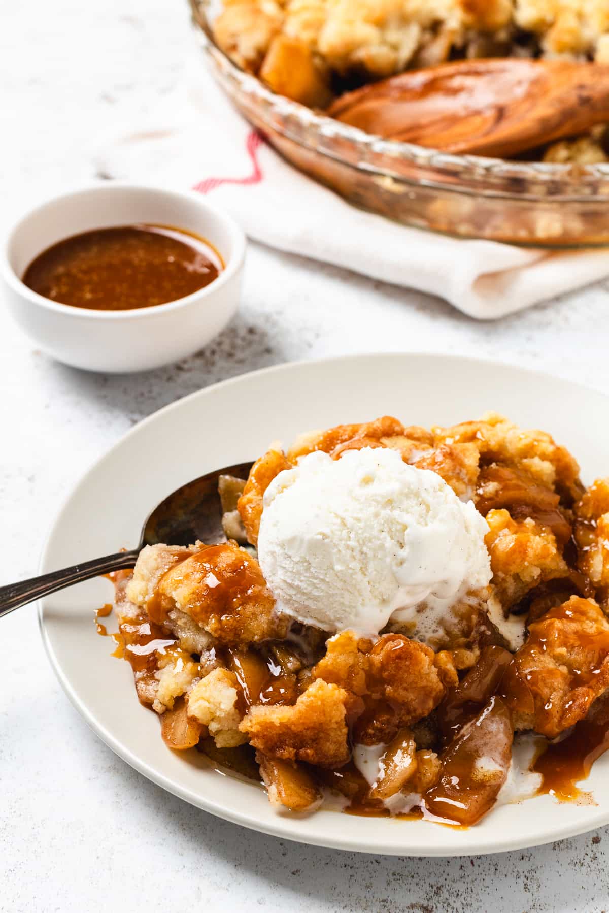 Warm caramel apple cobbler topped with vanilla ice cream and drizzled with rich caramel sauce.