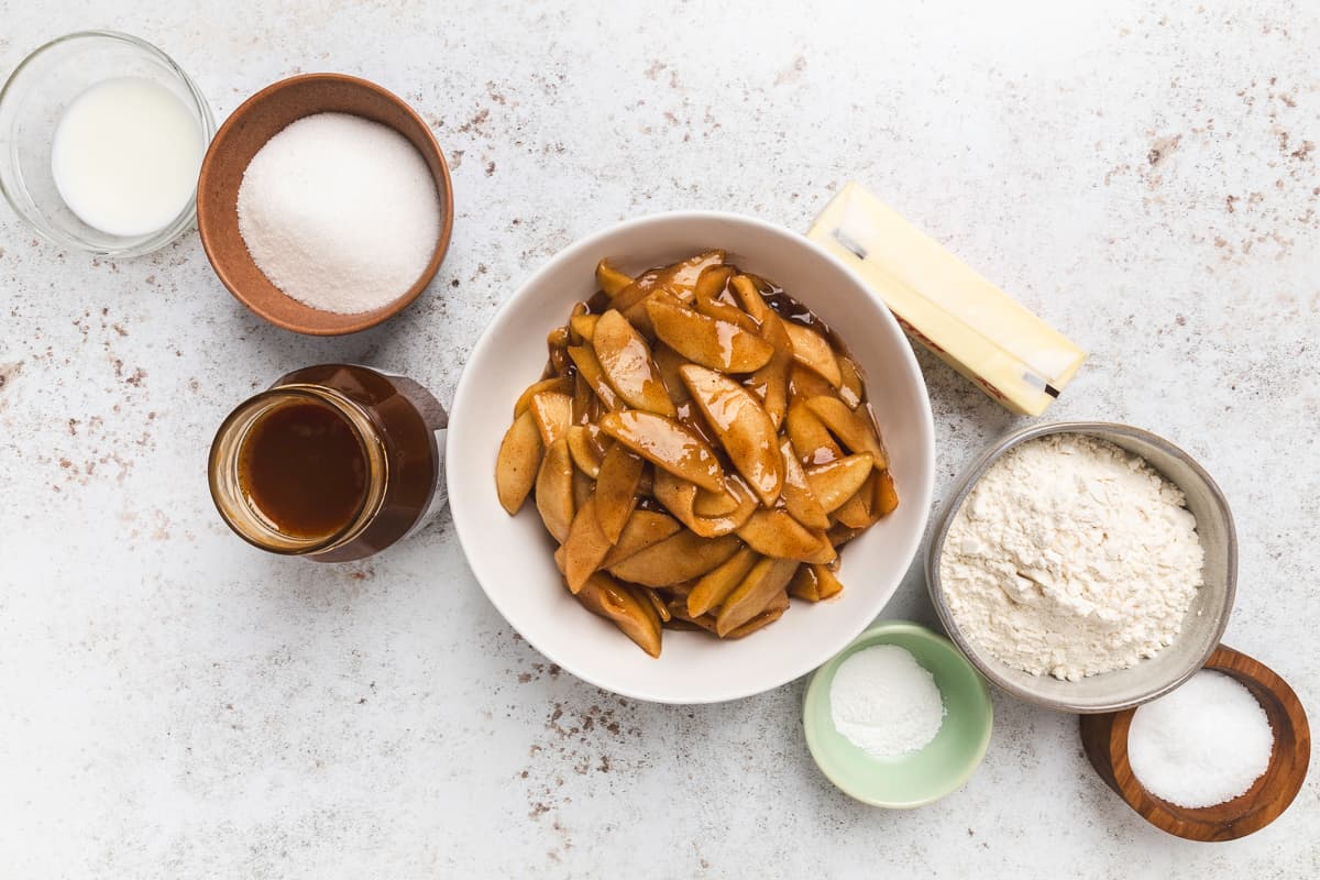 Overhead view of ingredients for caramel apple cobbler, including apples, caramel, and buttery topping mix.