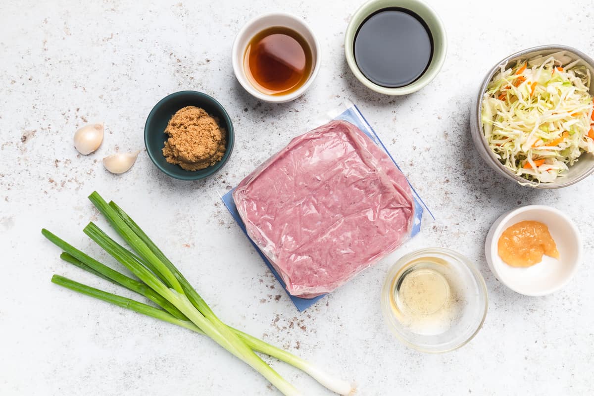 Raw ground turkey, green onions, garlic, cabbage mix, soy sauce, vinegar, brown sugar, and ginger paste on counter.