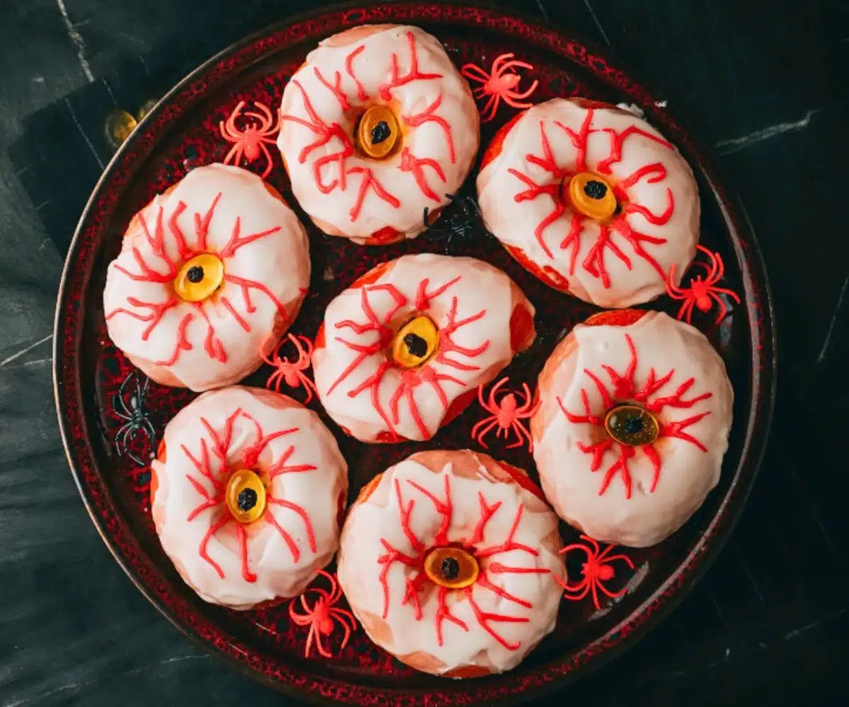 Creepy eyeball donuts with red icing veins and candy centers on a Halloween platter.