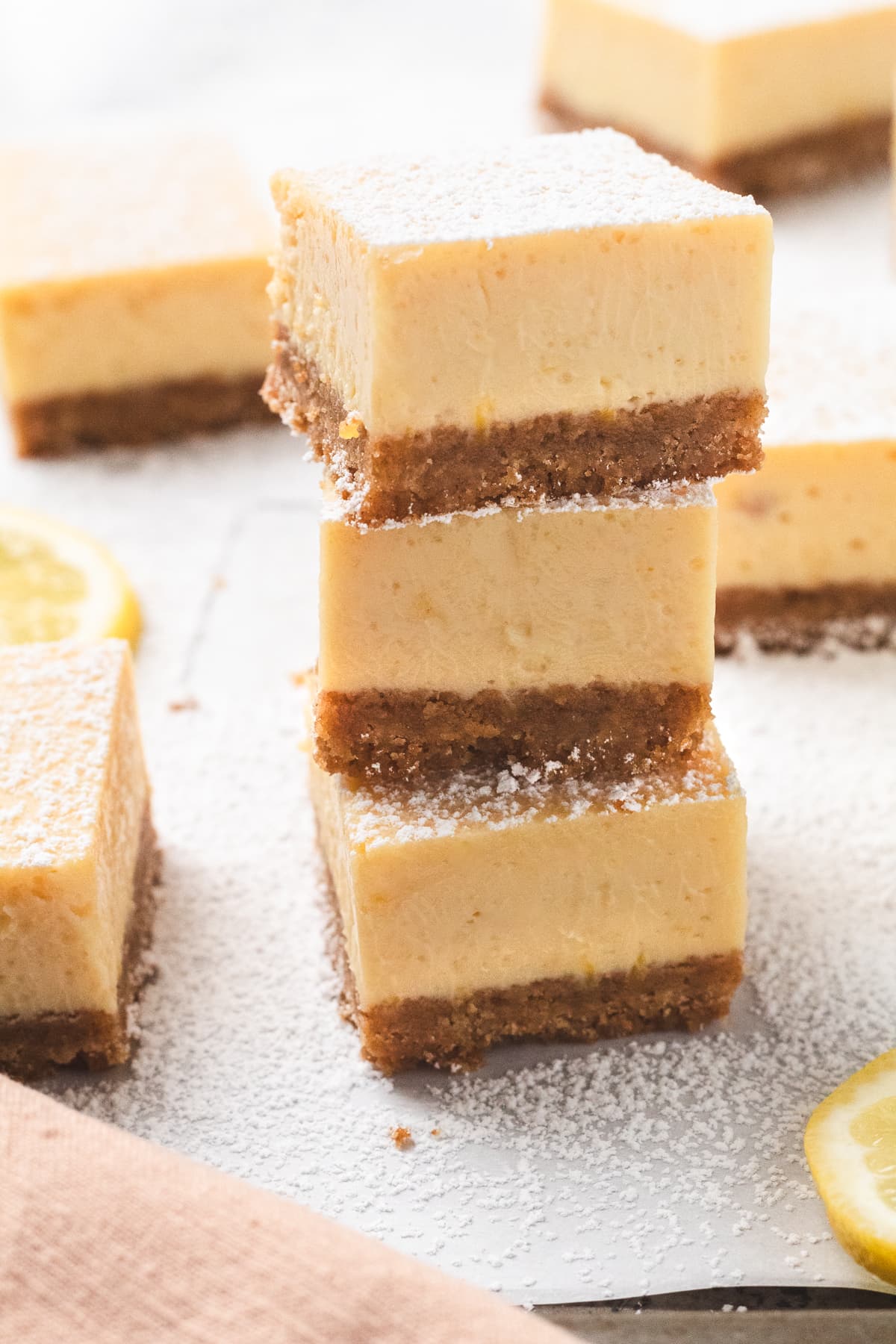Stack of lemon bars with graham cracker crust dusted with powdered sugar.